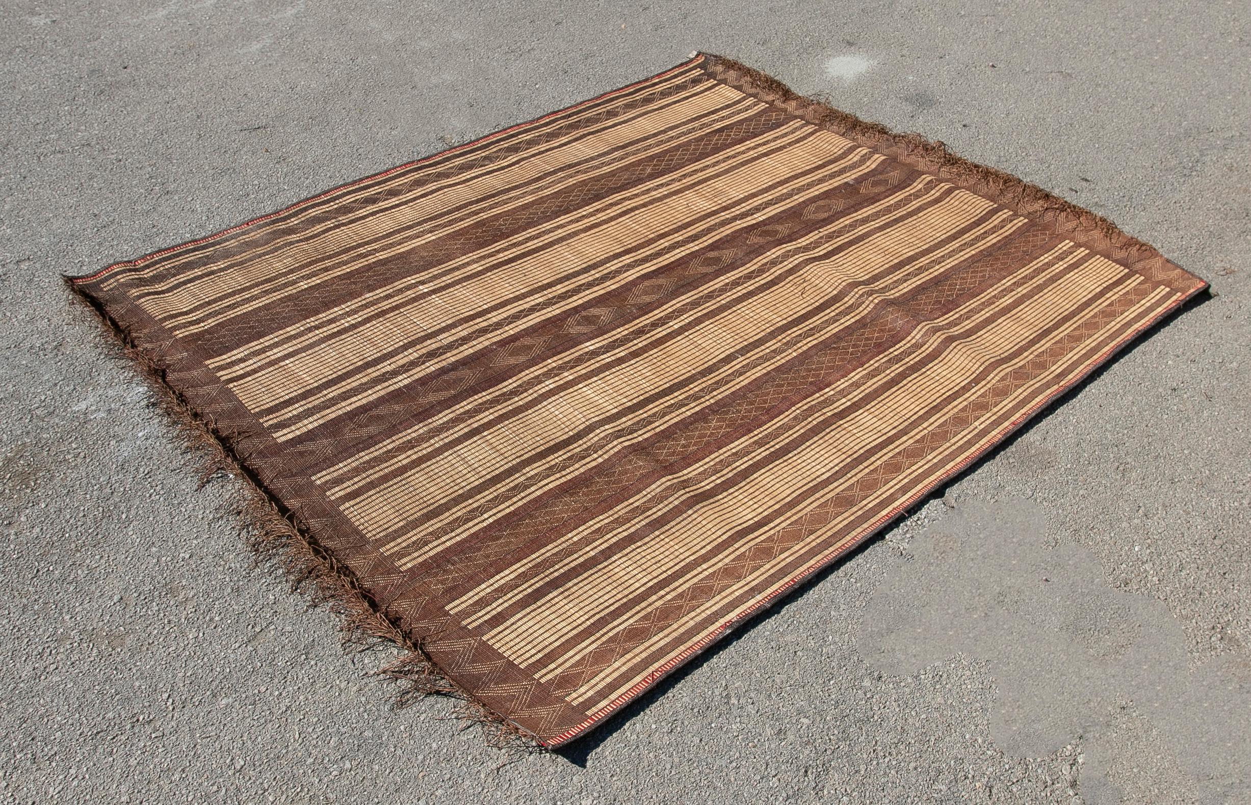 Moroccan Tuareg leather mats are made of dwarf palm tree fibers and hand woven with leather stripes, this are great to use indoor or outdoor, beautiful brown earth-tone colors. This vintage midcentury carpets are made in the desert of Morocco near