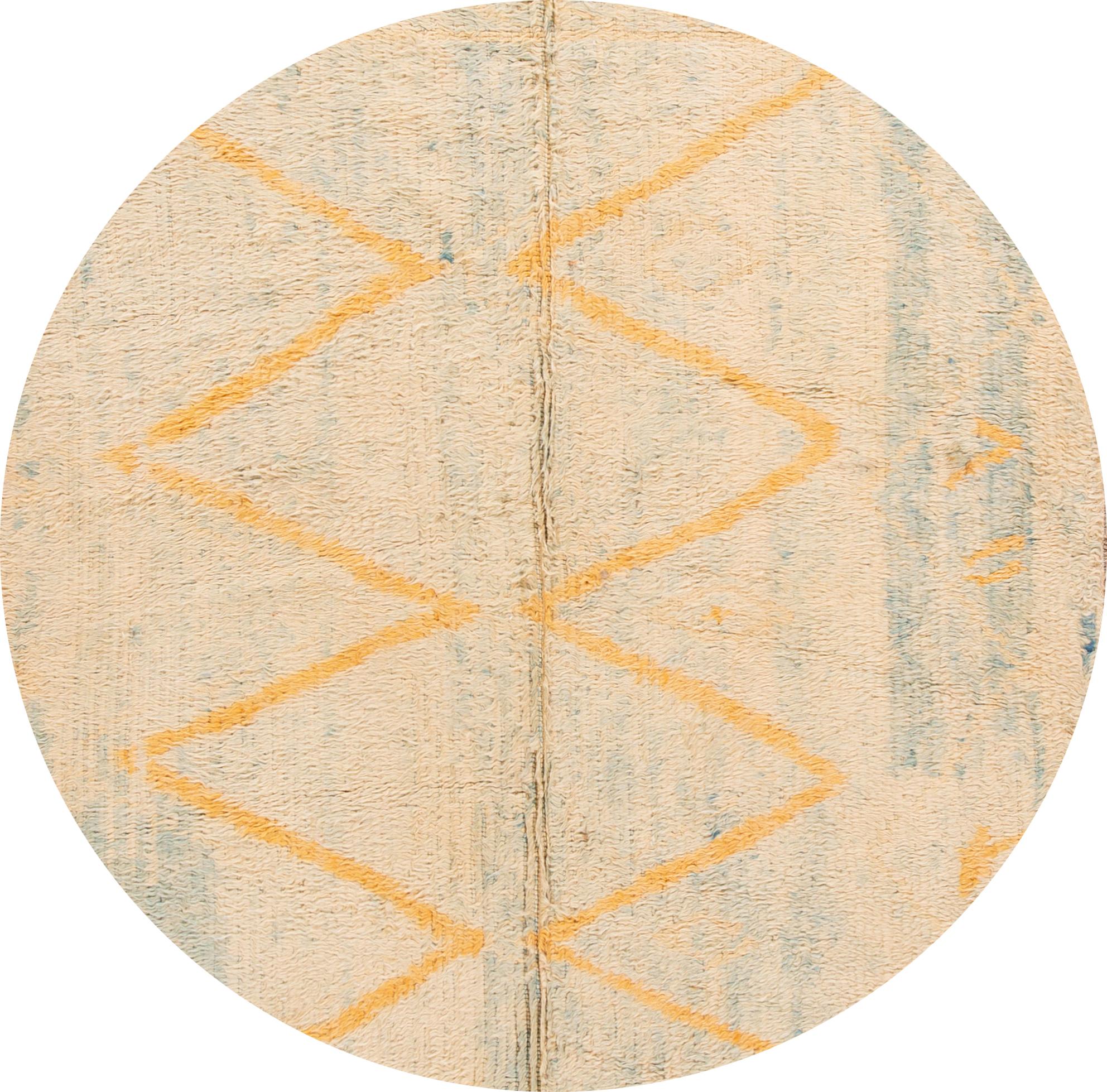 A mid-20th century hand knotted Moroccan rug with a peach field, orange and blue accents in a geometric design. 

This rug measures: 6'4