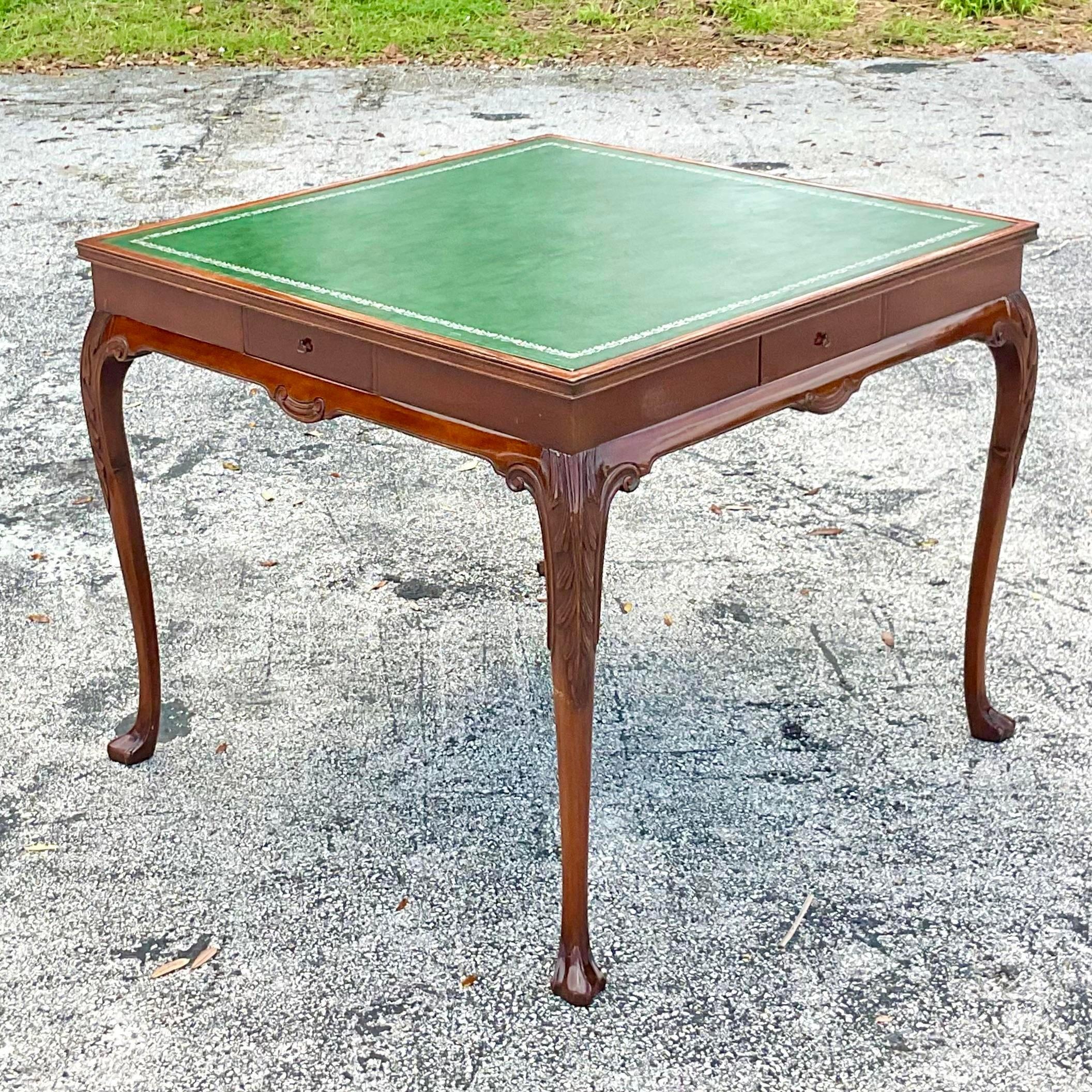 A fabulous vintage Regency game table. A chic Hunter green leather top with hand tooled silver leaf embossing. Hand carved detail on Cabriolet legs. Acquired from a Palm Beach estate.