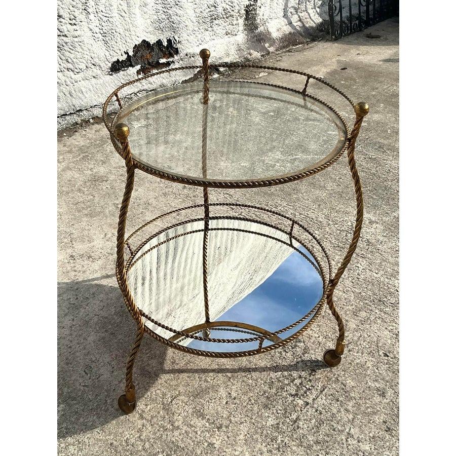 Apportez sophistication et charme à votre espace avec cet exquis chariot de bar vintage Regency torsadé et doré. Son design élégant se caractérise par un travail de métal doré torsadé, créant ainsi une pièce intemporelle à la fois fonctionnelle et