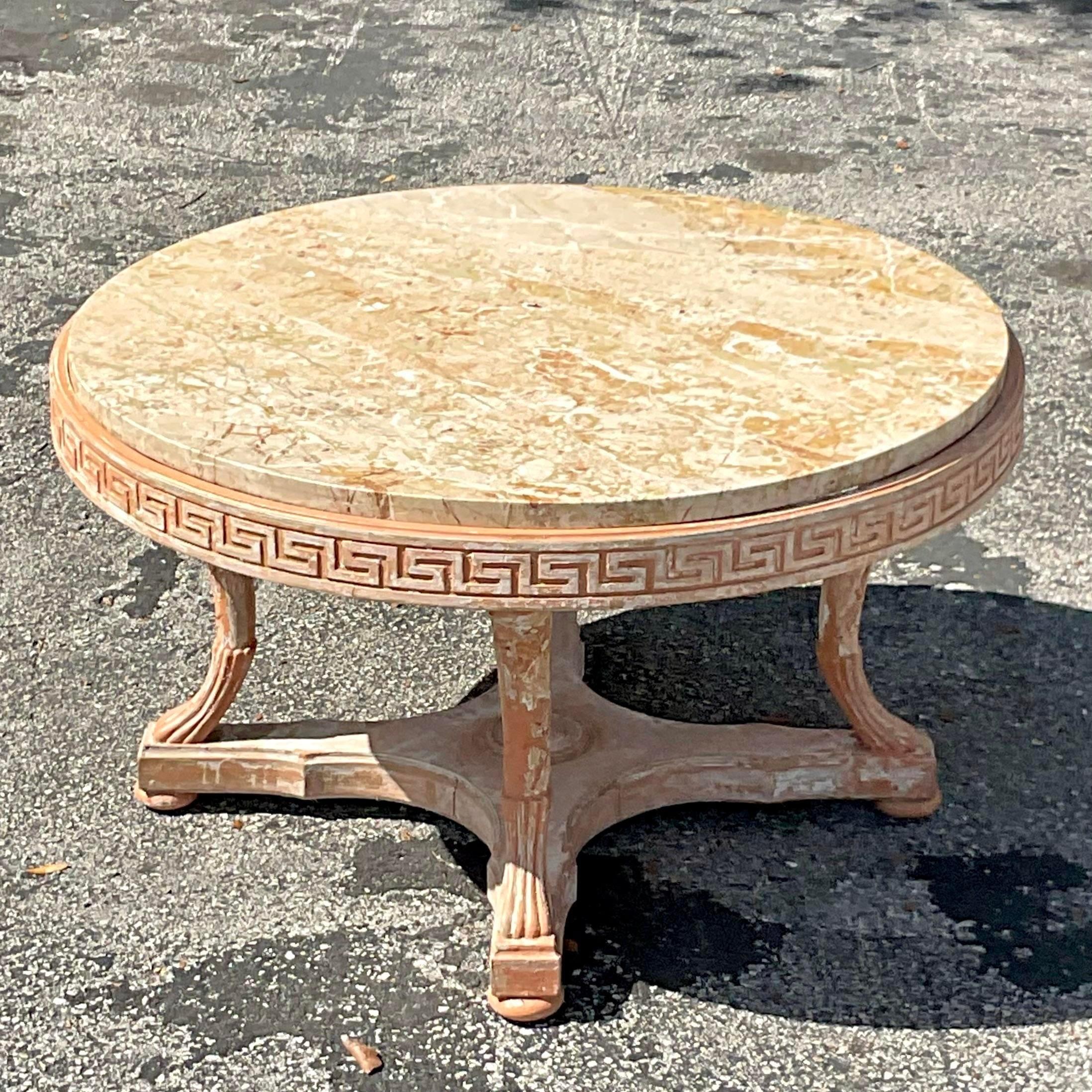 A fabulous vintage Regency coffee table. A chic carved Greek Key band around a faux finished pedestal. Inset marble top. Acquired from a Palm Beach estate. 