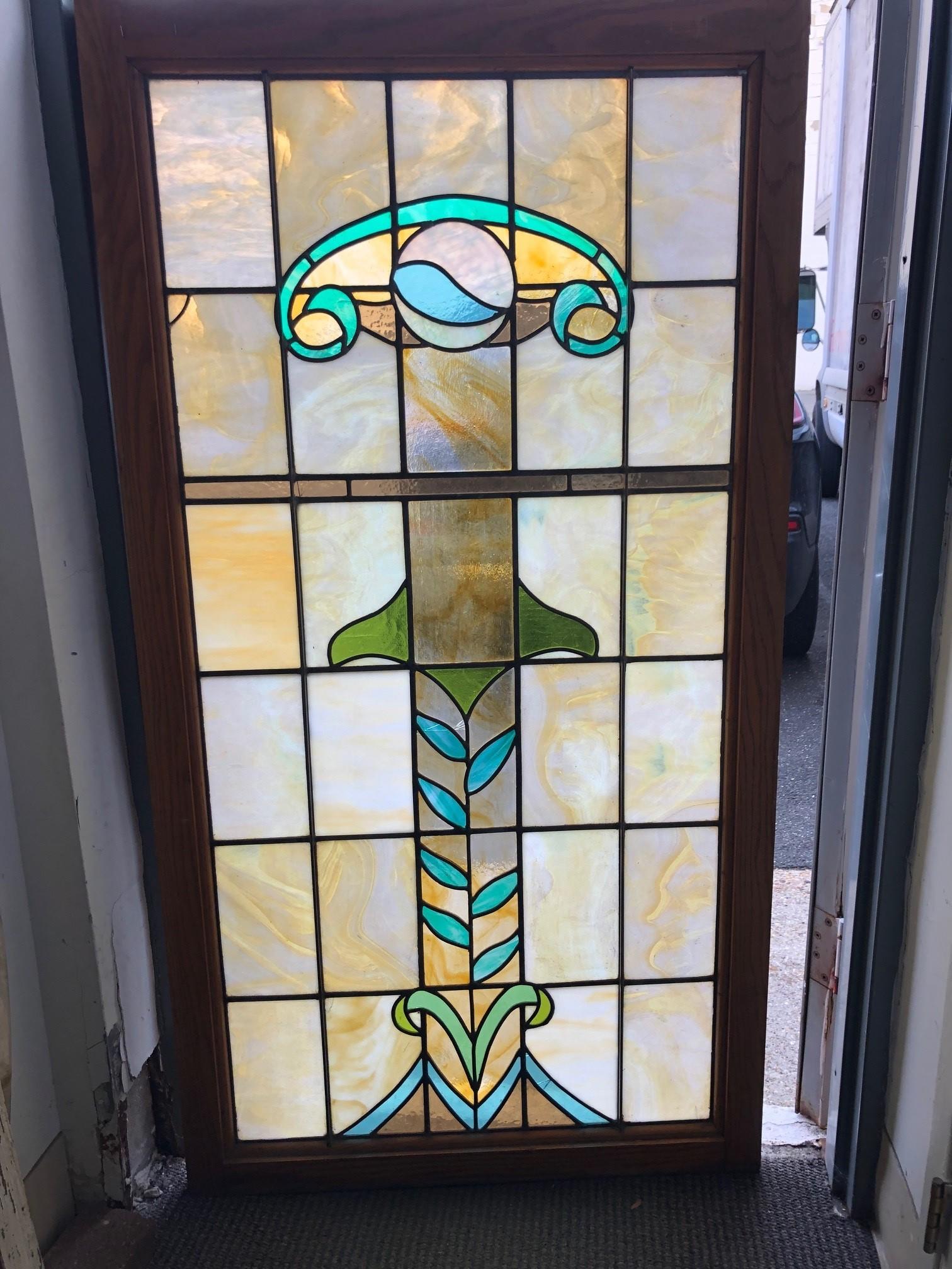 Mid 20th Century stained glass window in a oak frame. This is a very nice window with simply designs and colors which looks great in the light. The window does have a five small breaks but is overall in good shape and very sturdy, this window is