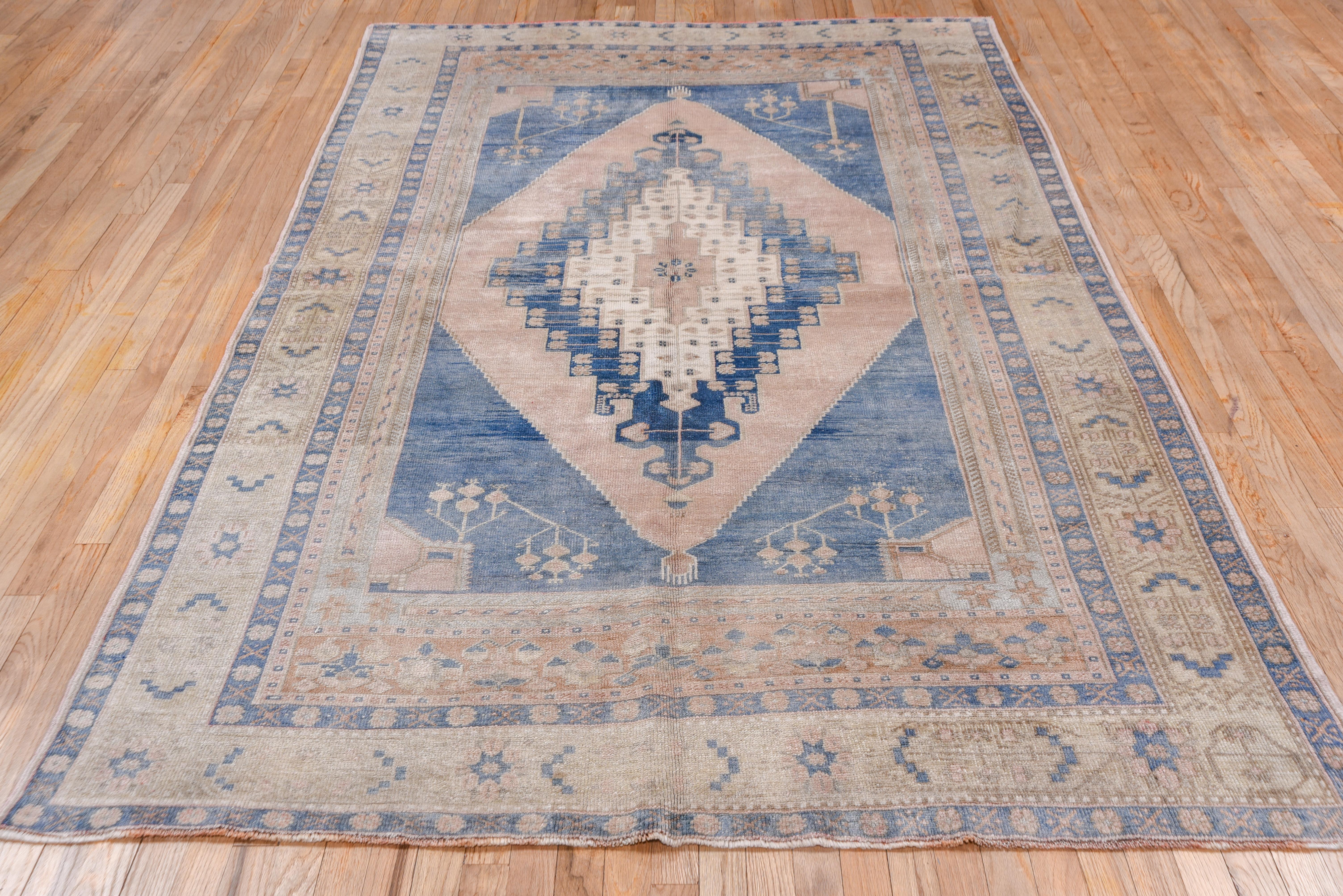 Conjoint light blue connects with floral decor set off the stepped and nested slate blue and ecru tall lozenge medallion on the light buff ground. At each field end of this Anatolian village piece is a floral panel. Bold design with modulated