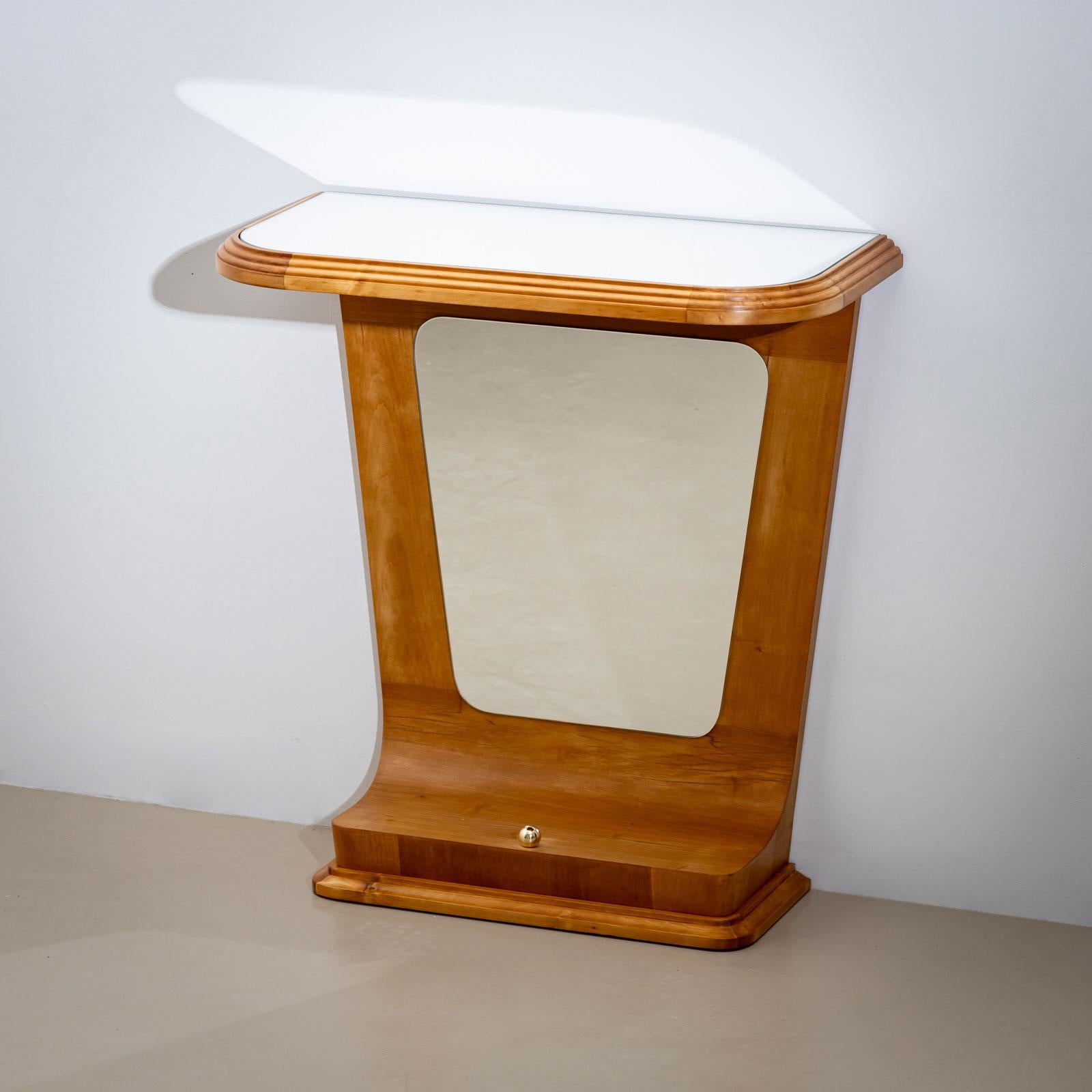 A small wall console made of cherrywood, featuring a glass top and a trapezoidal frame. The back panel is mirrored, creating an elegant sense of depth. The console has been hand-polished and is in move-in-ready condition.