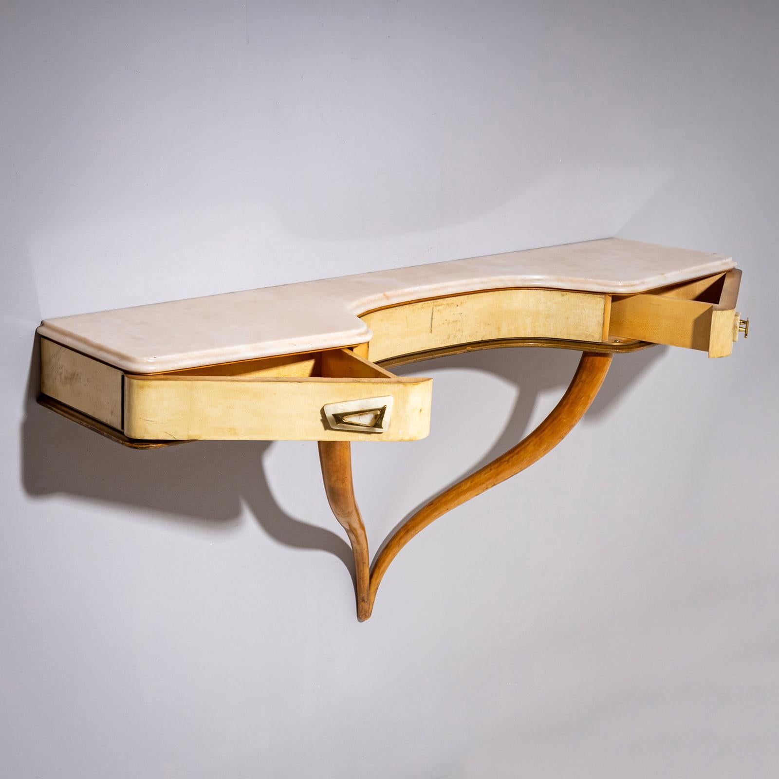Consola de pared de mediados de siglo con patas curvadas y cuerpo recubierto de pergamino con dos cajones, que se despliegan elegantemente en una esquina cada uno. La parte superior es de ónice beige. Las asas también son de latón y ónice. La