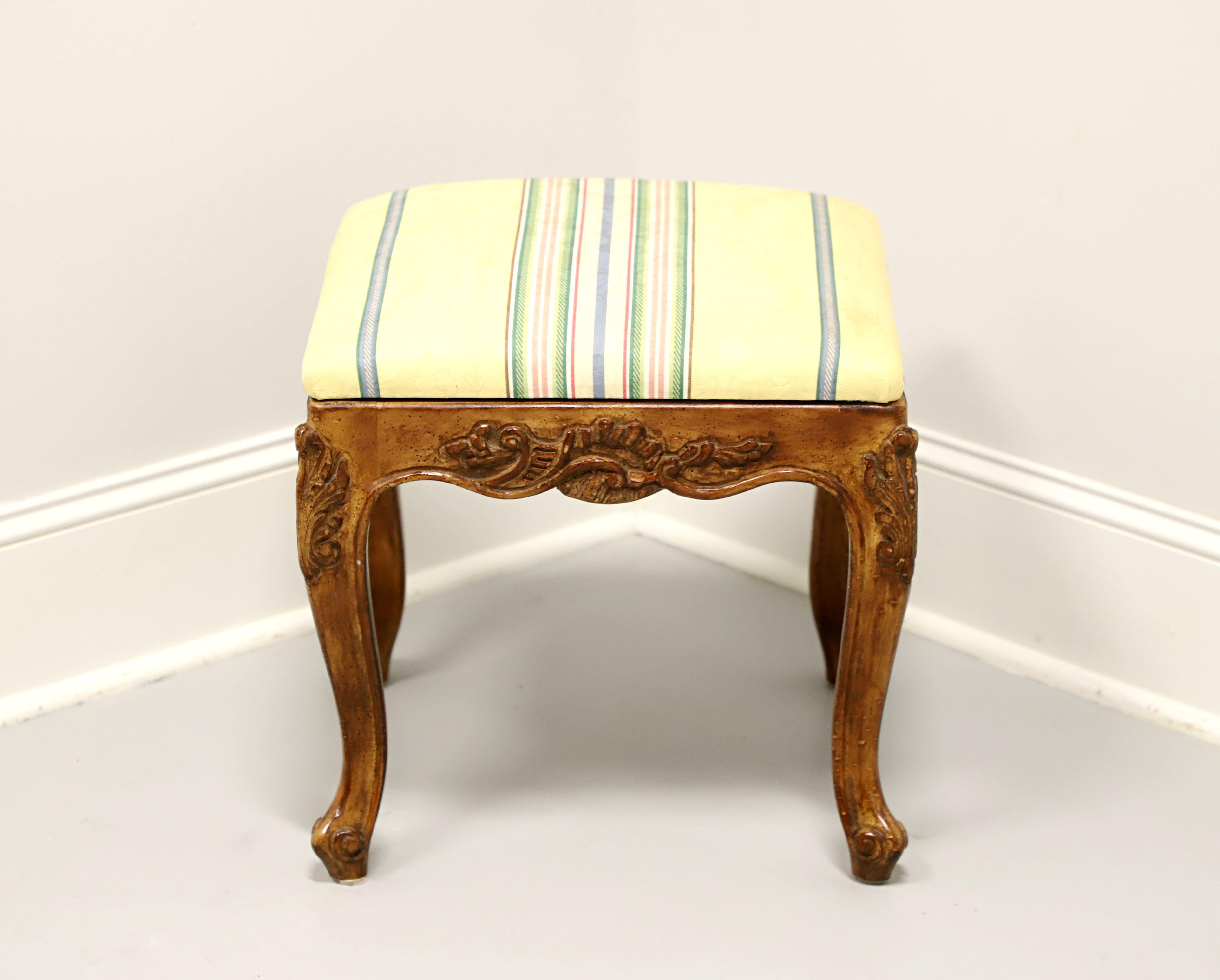 A French Country style bench footstool, unbranded, similar quality to Henredon. Walnut with a distressed finish, yellow, blue, pink, green, white color striped fabric upholstered seat, carved apron & knees, curved legs and scroll feet. Made in the
