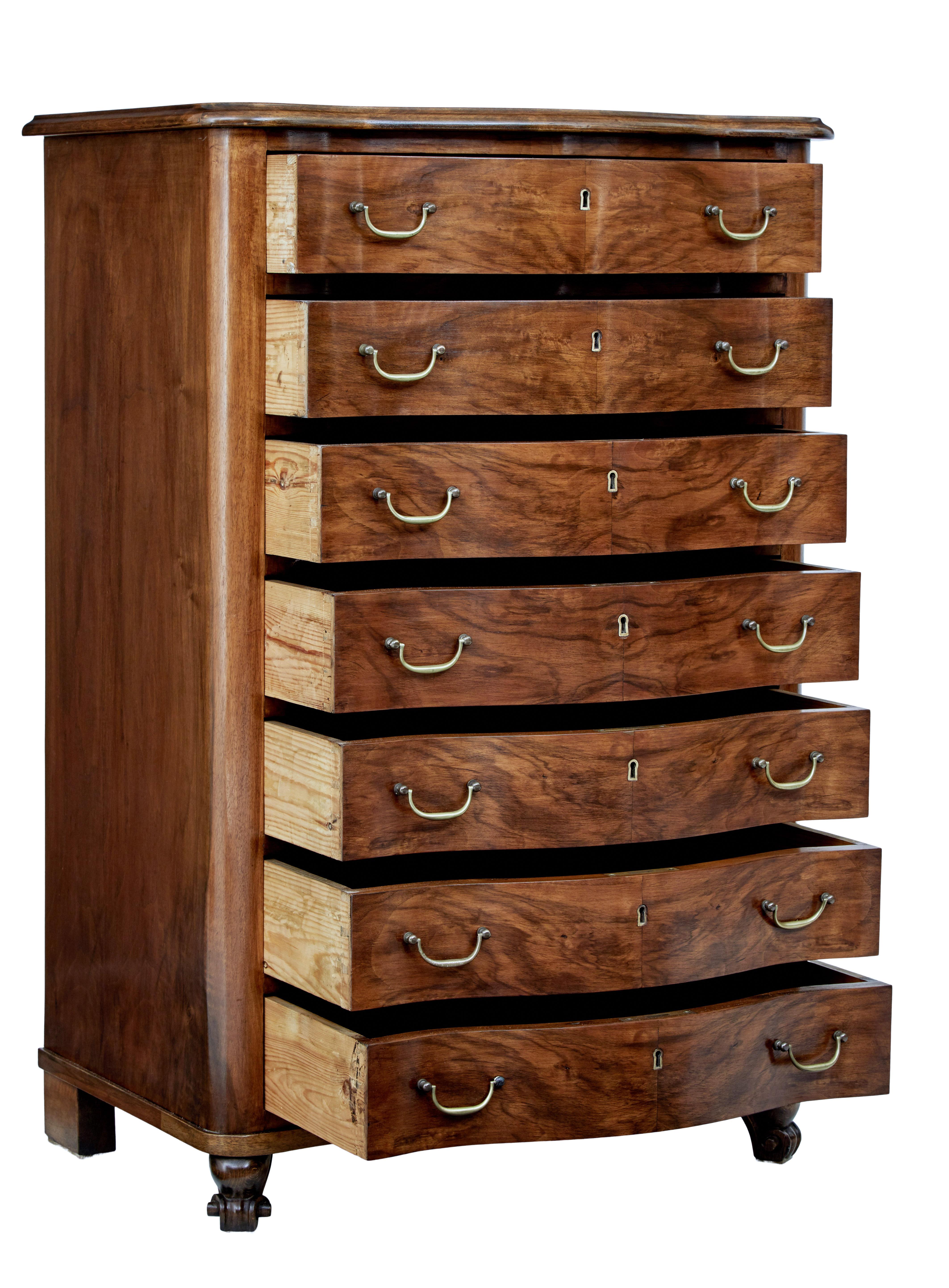 Mid-20th century walnut tall chest of drawers, circa 1950.

Fine quality serpentine shaped 7-drawer chest. All drawers of equal proportions with burr walnut veneers, each fitted with brass swan neck handles.

Standing on carved front legs, with