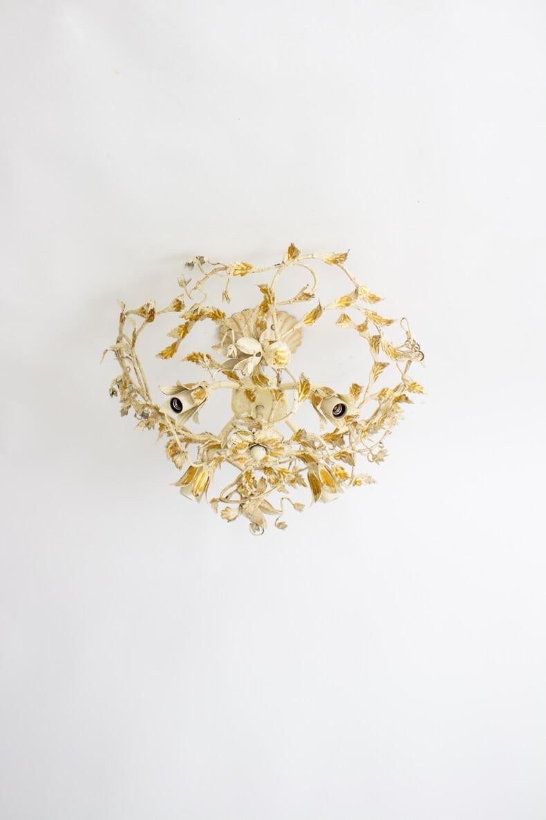 A mid-20th century white and gold tole flush mount fixture. Metal painted off white with gold leaf ornamentation. Four lights, entwined with branches and flowers. The fixture is open and airy. Italian, Mid 20th Century. Cleaned and rewired with new