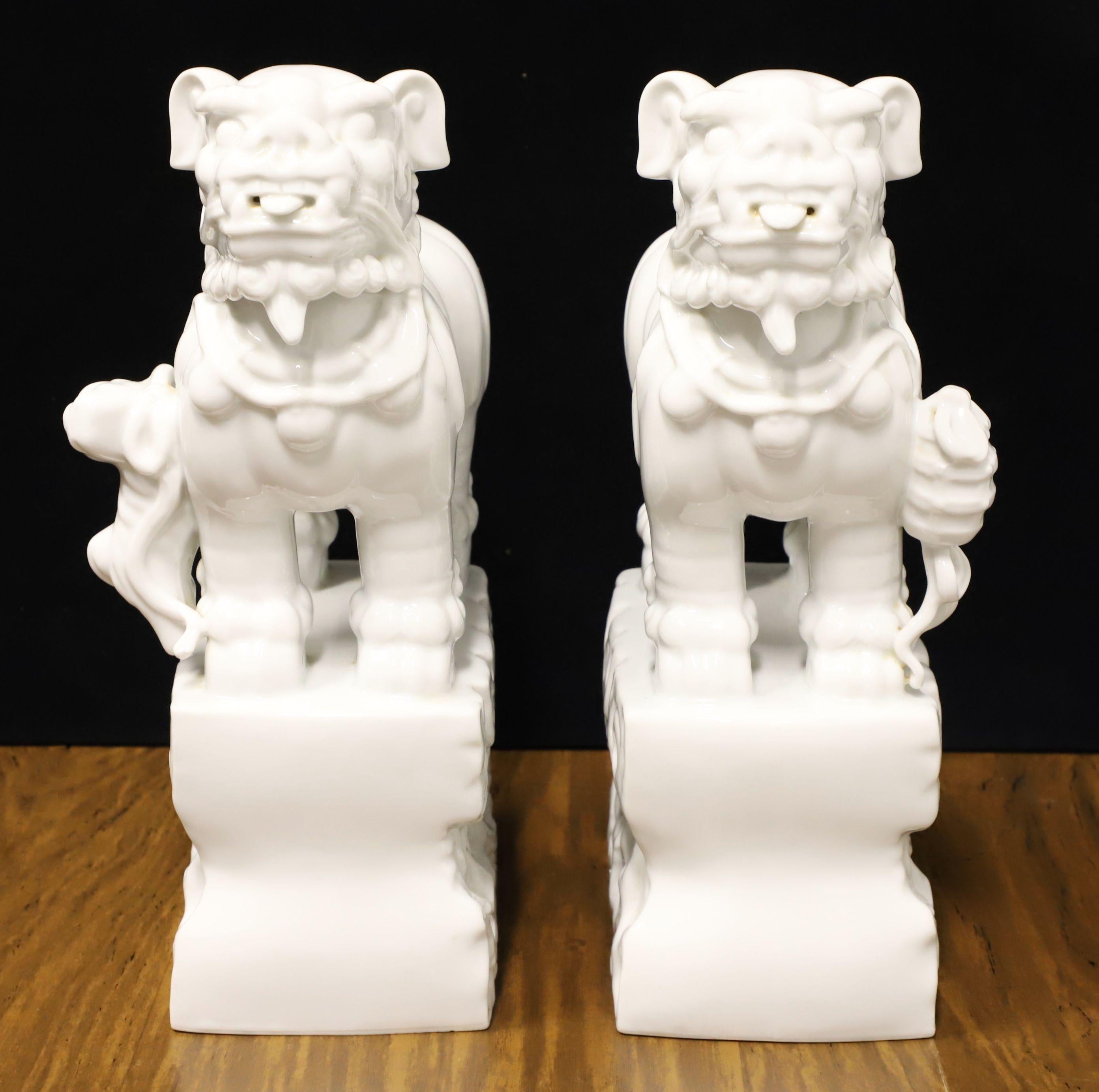 A pair of Foo Dogs in porcelain depicting mythical lion-like animals that are protectors, 