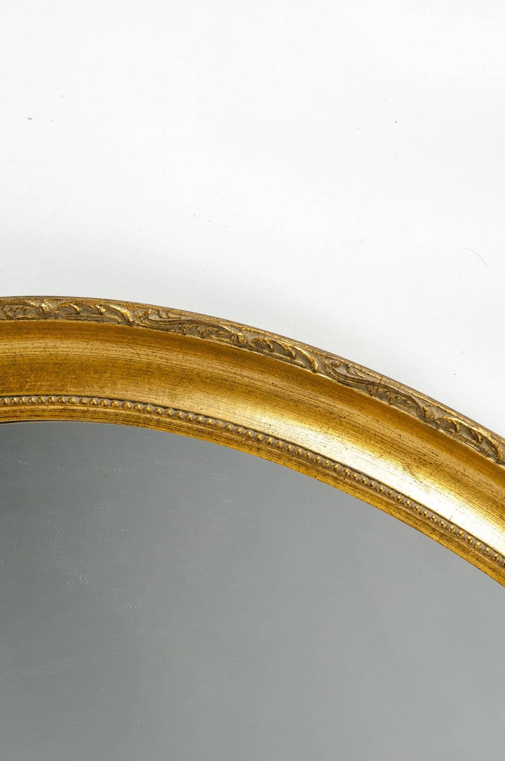 Mid-20th century gilded wood frame oval shape hanging mantel wall mirror. The oval mirror measure about 44 inches Length X 34 inches Width X 2.7 inches dept of the frame .