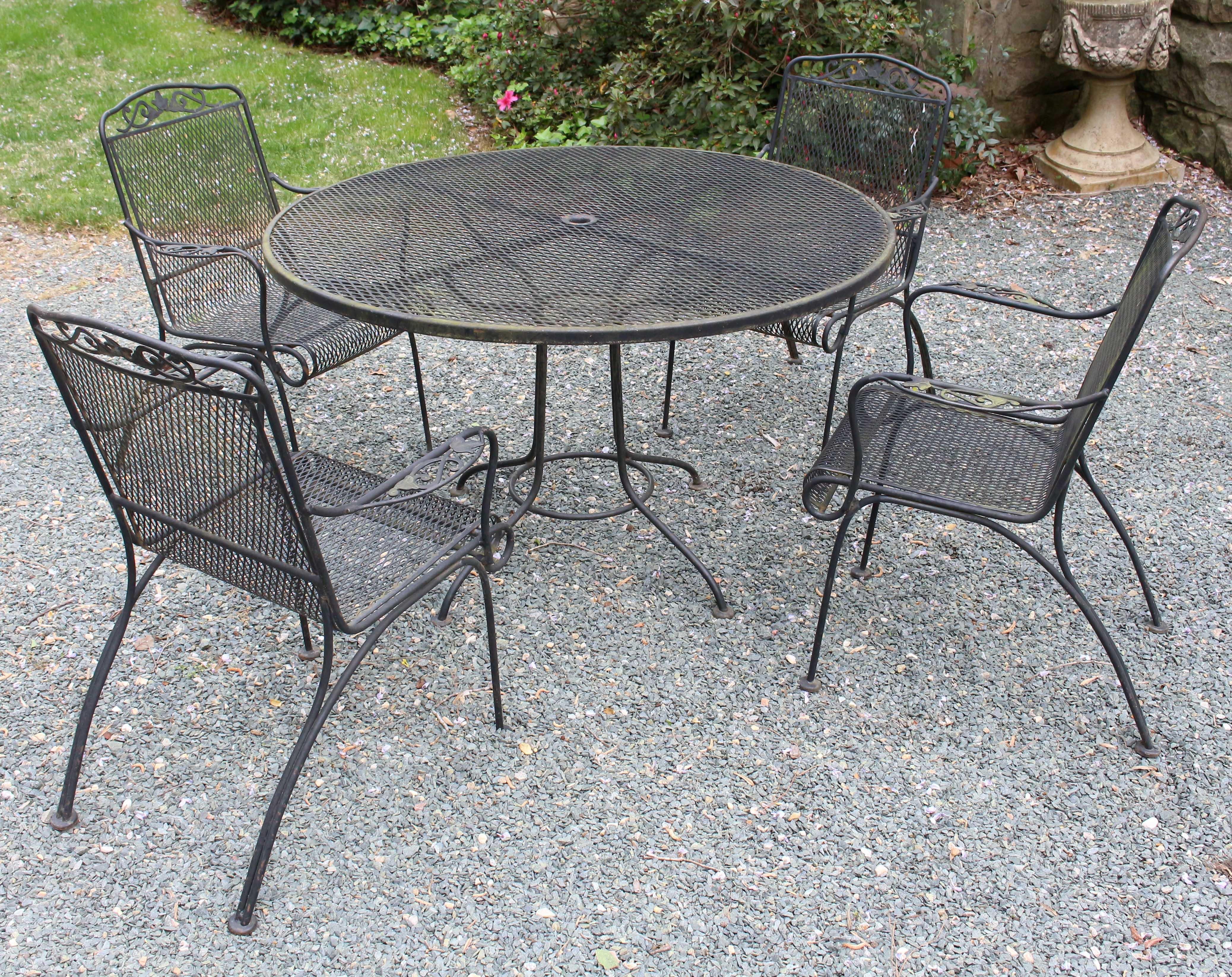 Mid-20th century Woodard wrought iron table & 4 arm chairs. Ivy motifs; scroll & roll arms. Black paint, weathered patina.
Table: 47
