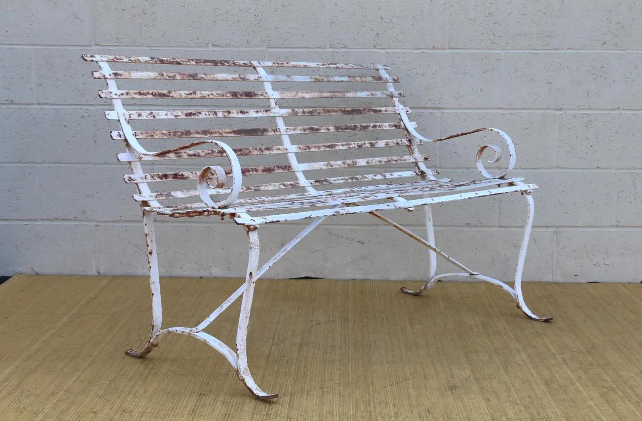 Beautiful wrought iron outdoor bench. In vintage condition with original patina. Wonderful design and great detailing work. 
Dimensions: 
47.5in L” x 24in D” x 31in H” 
16.5in SH” x 16in SD” x 42in SW” 
23in AH”
