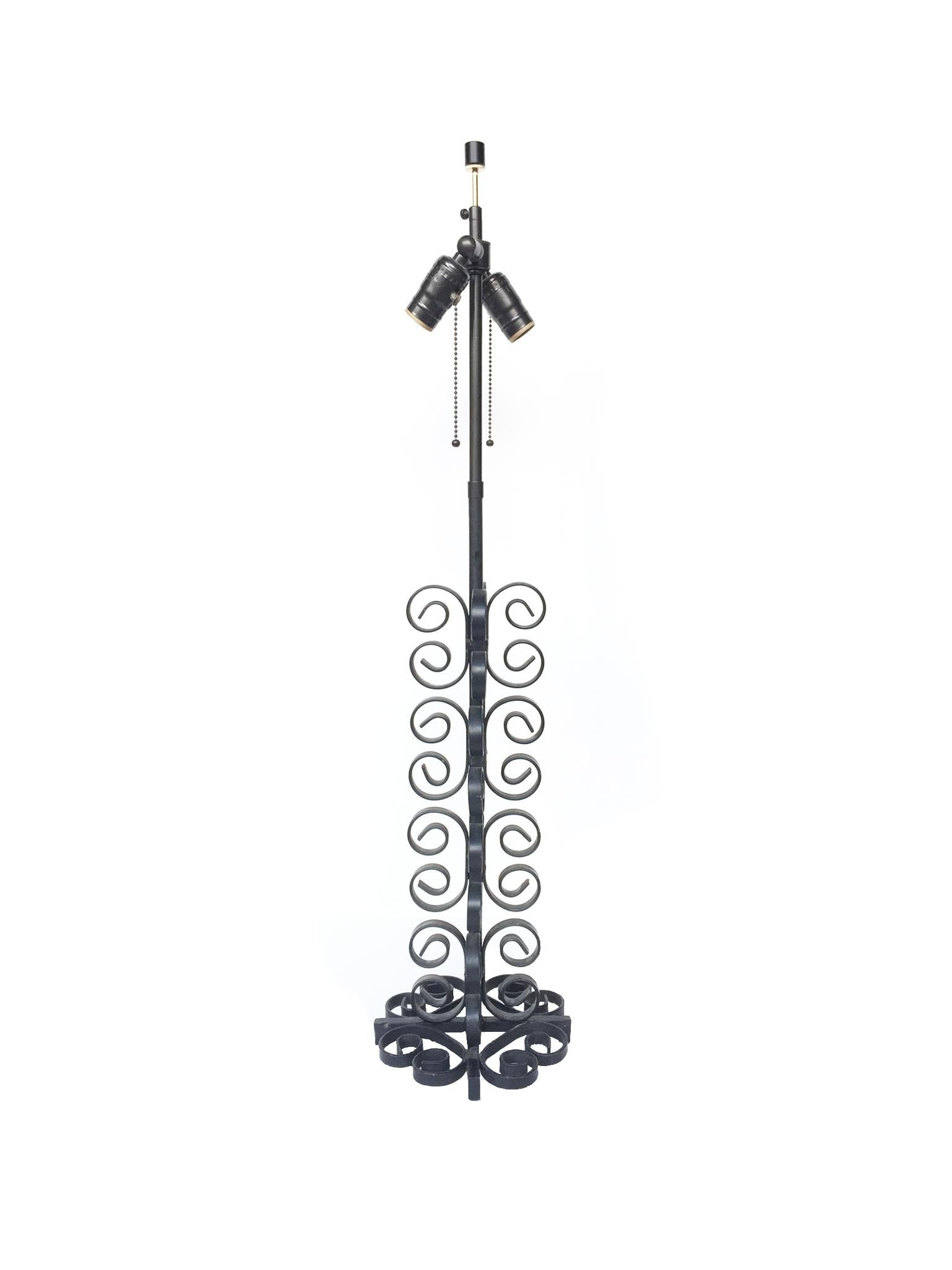 An elegant table lamp designed in the whimsical style of Art Deco designer Paul Kiss. This lamp is comprised of patinated black wrought iron base shaped into a column of openwork scrolls. The custom white linen shade is new. The lamp is also newly