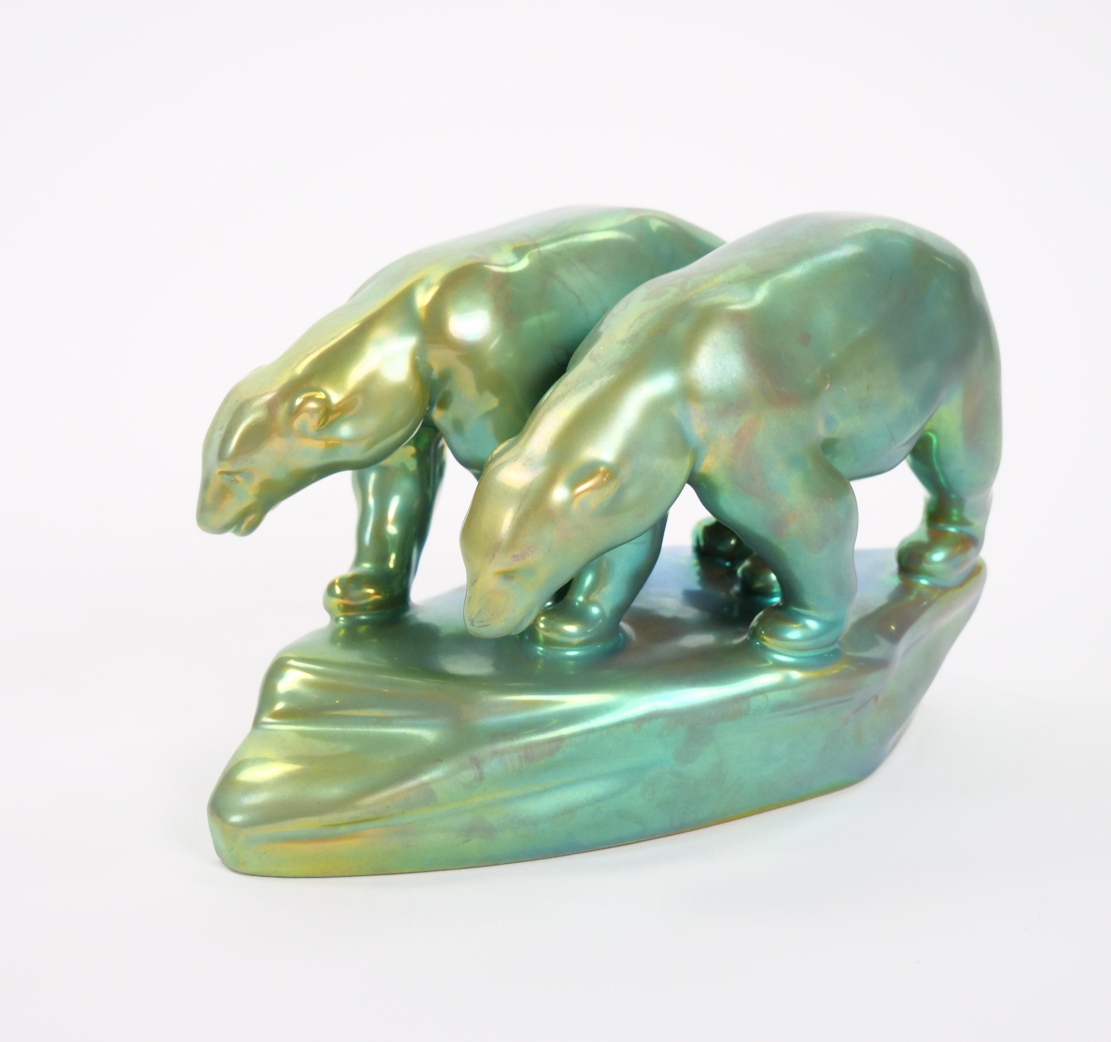 Charmante sculpture en porcelaine hongroise du milieu du XXe siècle, conçue par Mihály Nagy pour la célèbre manufacture Zsolnay. Cette pièce captivante représente deux ours polaires perchés au sommet d'une forme abstraite d'iceberg, rendue dans la