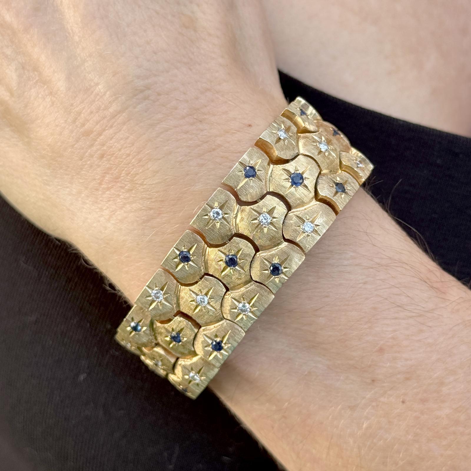 Dieses breite Gliederarmband aus 14 Karat Gelbgold mit Diamanten und Saphiren aus der Mitte des 20. Jahrhunderts bietet eine perfekte Mischung aus Eleganz und Vintage-Charme. Das Armband besteht aus 27 runden Diamanten im Brillantschliff von