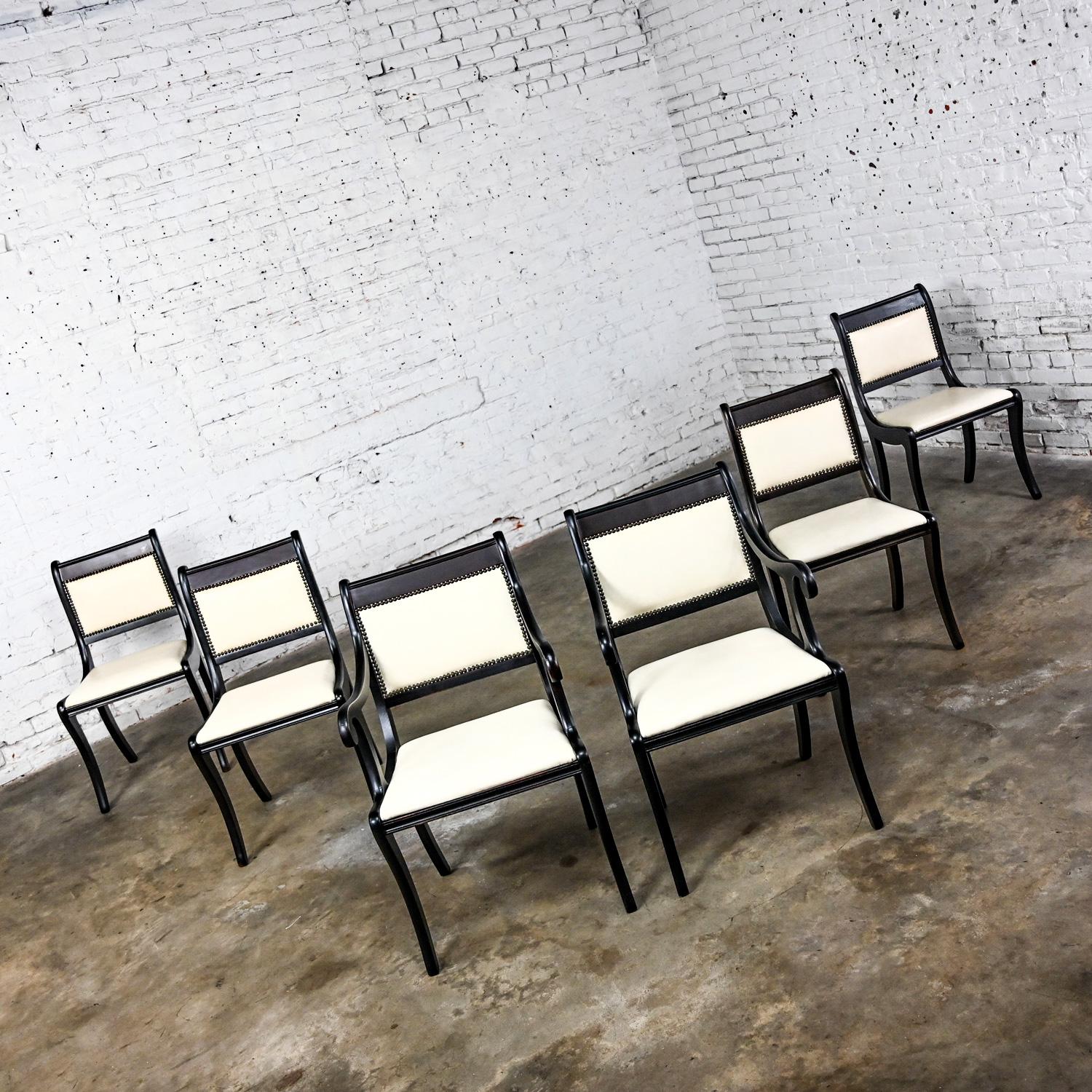 Gorgeous Mid Century Regency style dining chairs comprised of black dyed & distressed mahogany frames, off white vinyl or faux leather seats and backs with nail head details, 2 arm and 4 side chairs, set of 6. Beautiful condition, keeping in mind