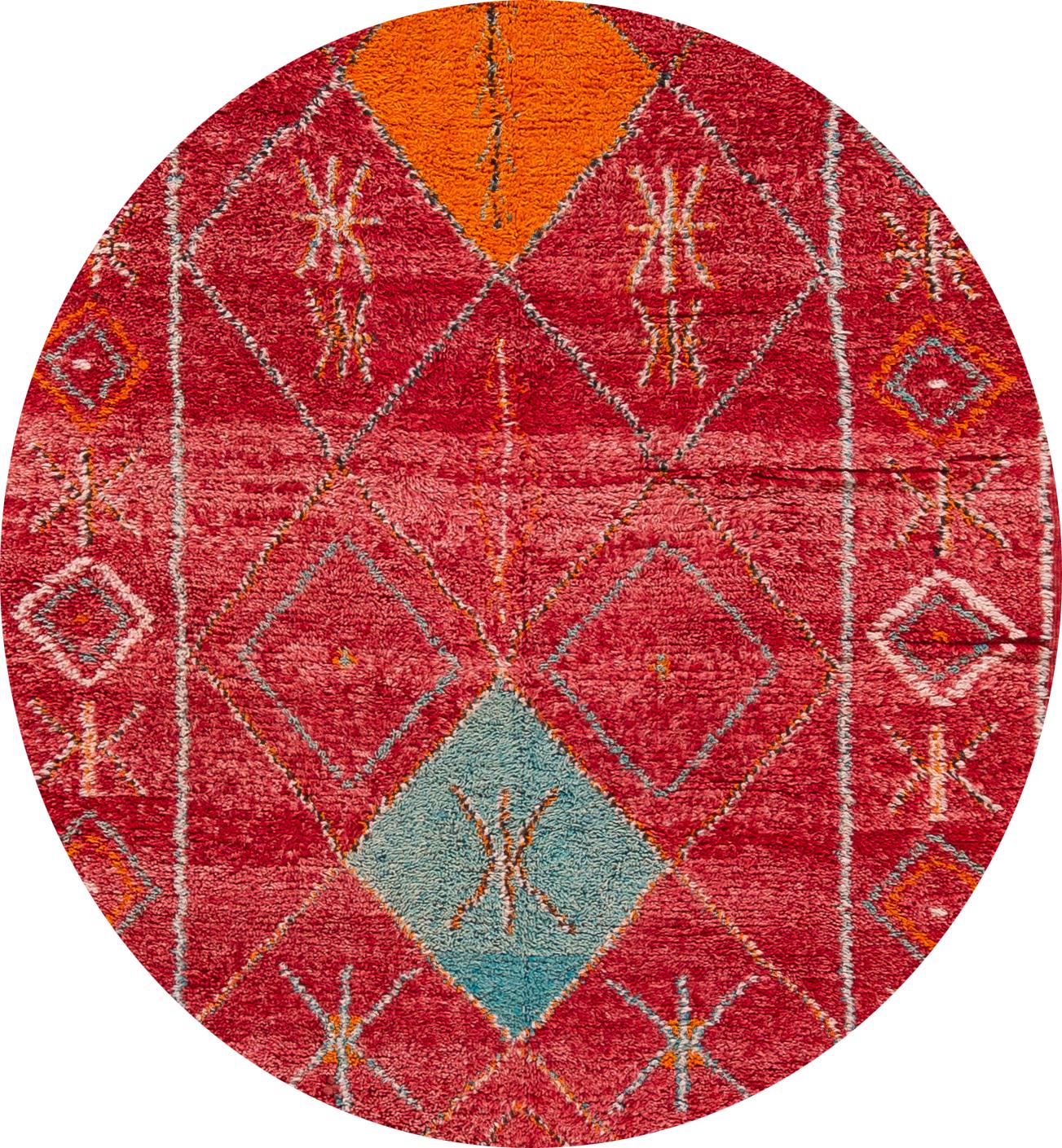 Magnifique tapis marocain vintage, en laine nouée à la main, avec un champ rouge vif, des accents orange et bleus dans un design à médaillons multiples,
vers 1980.
Ce tapis mesure 4' 7