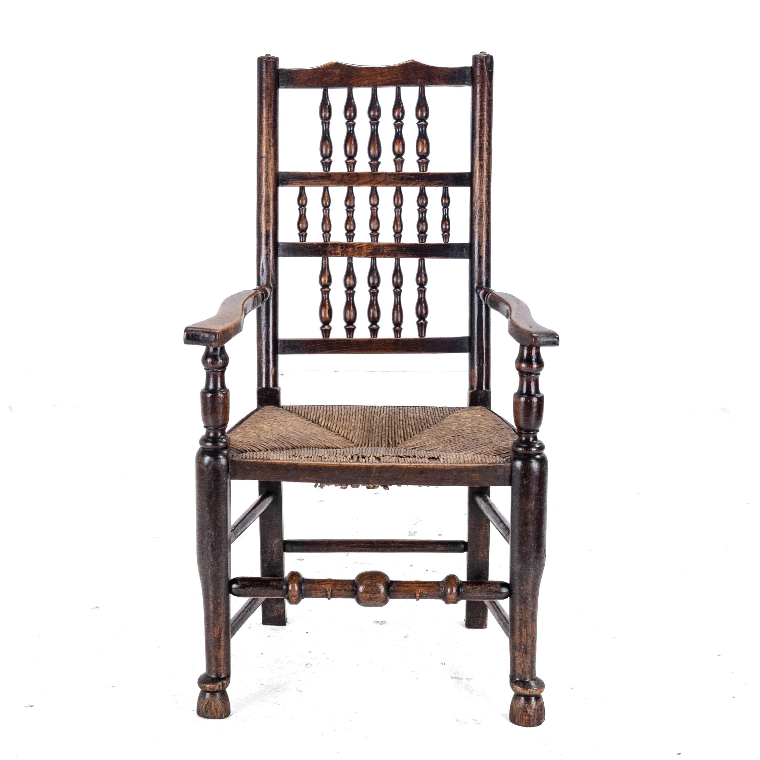 A mid C.19th, elm and ash framed, rush seated, Lancashire type, country elbow chair or carver armchair. This chair feature triple rows of turned spindles back, turned style uprights, open shaped arms with turned supports, over original rush woven