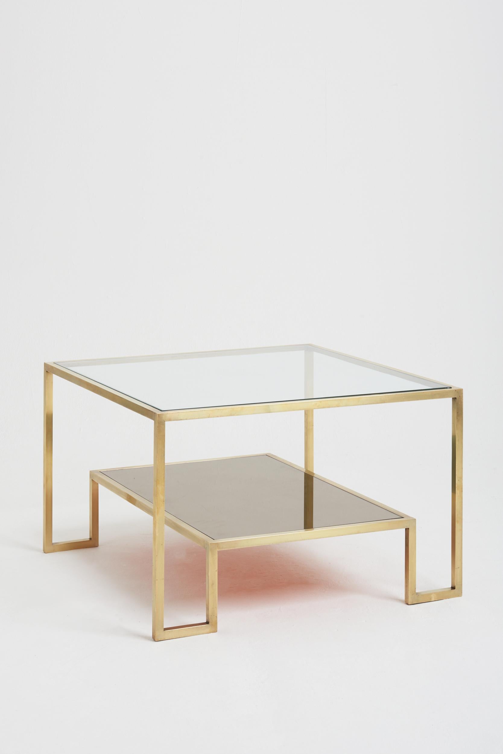A brass two-tiered square coffee table, glass top and mirrord lower tier.
France, Circa 1970.