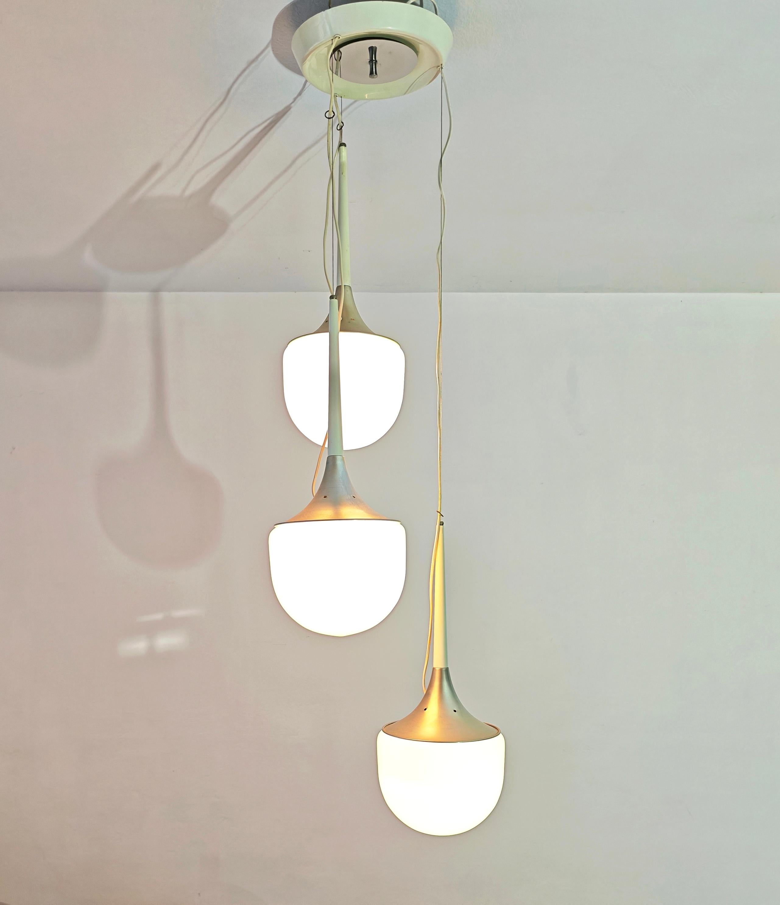 Sospensione pop di Esperia, realizzata in Italia negli anni Settanta. Caratterizzato da tre cascate con filo metallico che sostengono tre lampade in vetro al latte con un supporto in alluminio, con una parte smaltata. Rosone circolare smaltato e