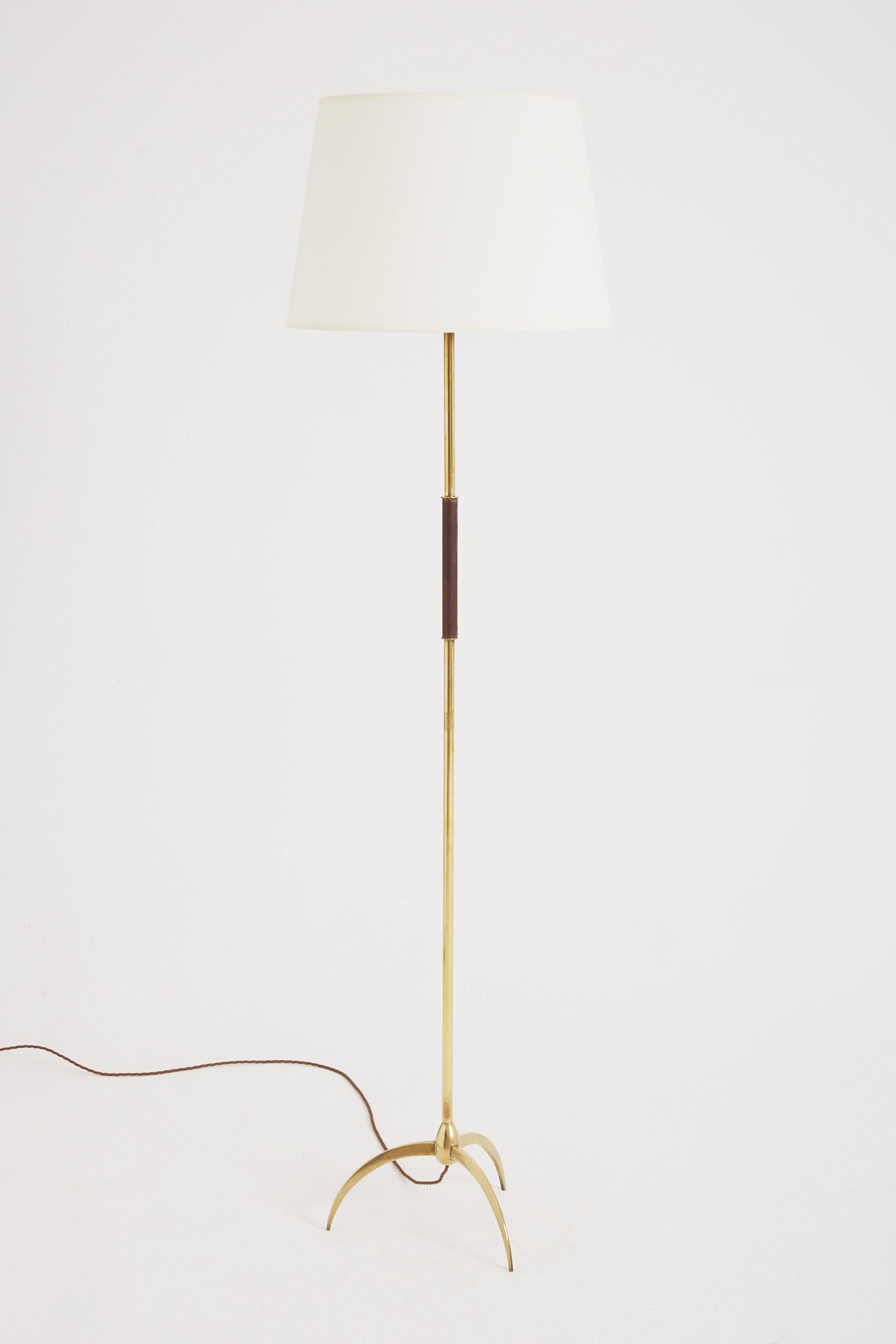 A brass tripod floor lamp, with a brown leather accent.
France, Circa 1950.