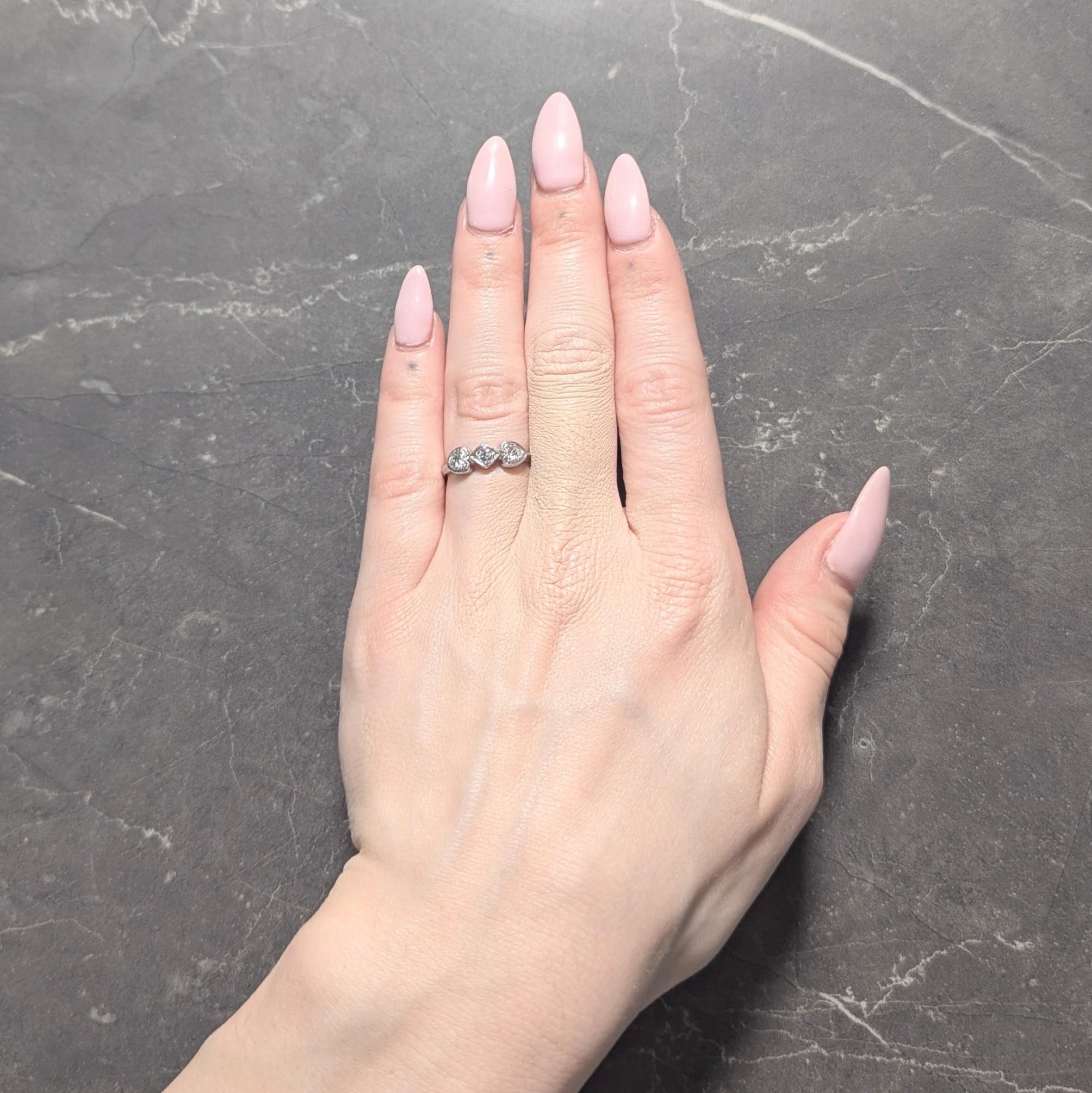 Featuring three transitional cut diamonds weighing approximately 0.32 carat total - G color with VS2 clarity
Bead set east to west in diamond and heart shaped forms with grooved profile
Completed by knife edge shank and high polish finish
Partially