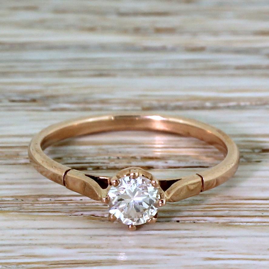 A gorgeous rose gold engagement ring. The white and bright transitional cut diamond in the centre is secured in an eight-claw coronet collet that sits nice and low to the finger, leading to a slim and taping court-shaped shank. A ring that manages