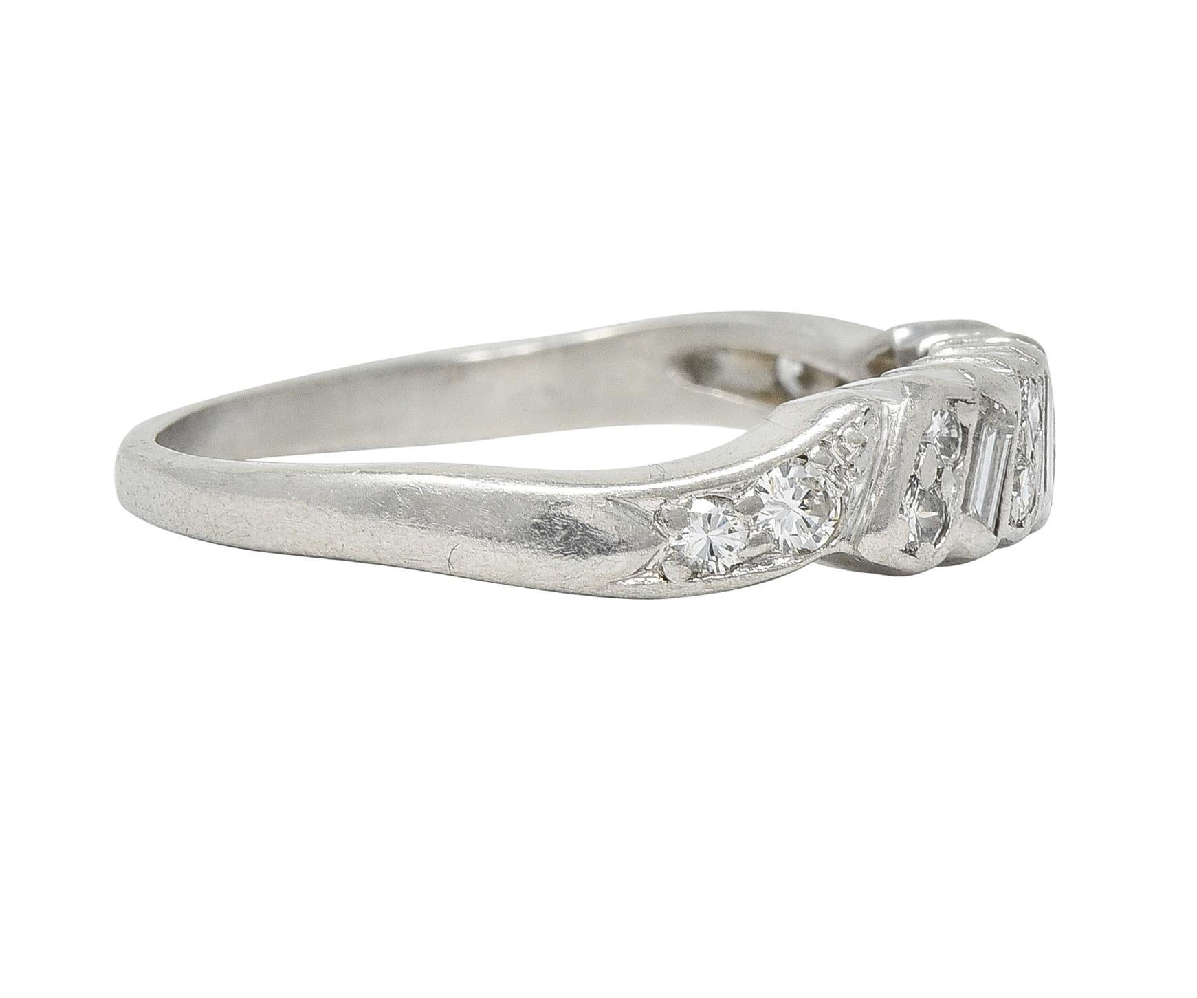 Designed as a folded ribbon motif with a baguette and round brilliant cut diamonds 
Weighing approximately 0.62 carat total - G color with VS2 clarity 
Bead and bezel set to the front and in swirling shoulders
Stamped for platinum
Circa: 1950s
Ring