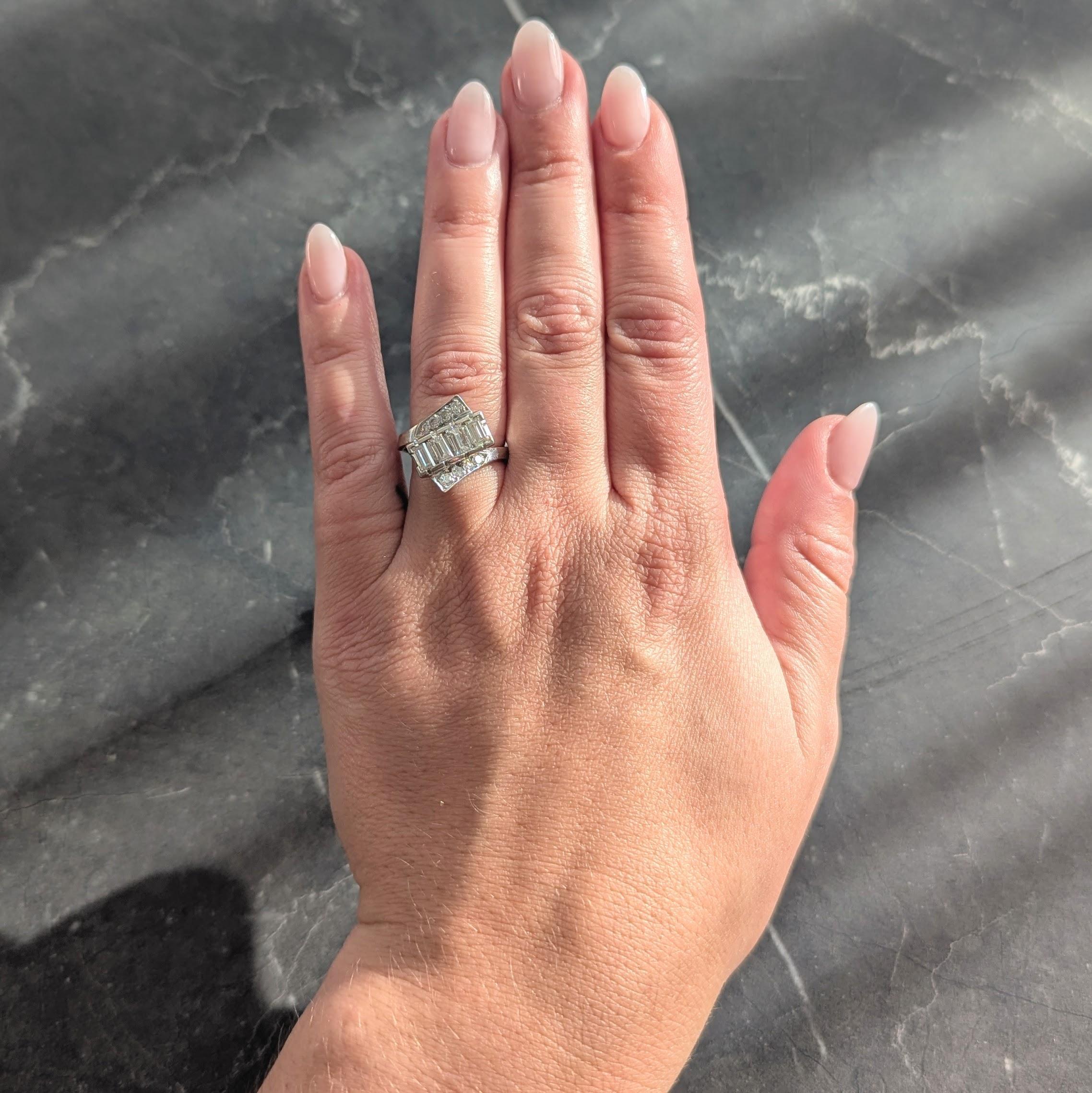 Ring im Bypass-Stil mit einer Reihe von Diamanten im Baguetteschliff in der Mitte
Mit einem Gesamtgewicht von ca. 0,80 Karat - Farbe G/H mit Reinheit VS1
Flankiert von ausladenden, bandförmigen Schultern, die mit Diamanten im Einzelschliff besetzt