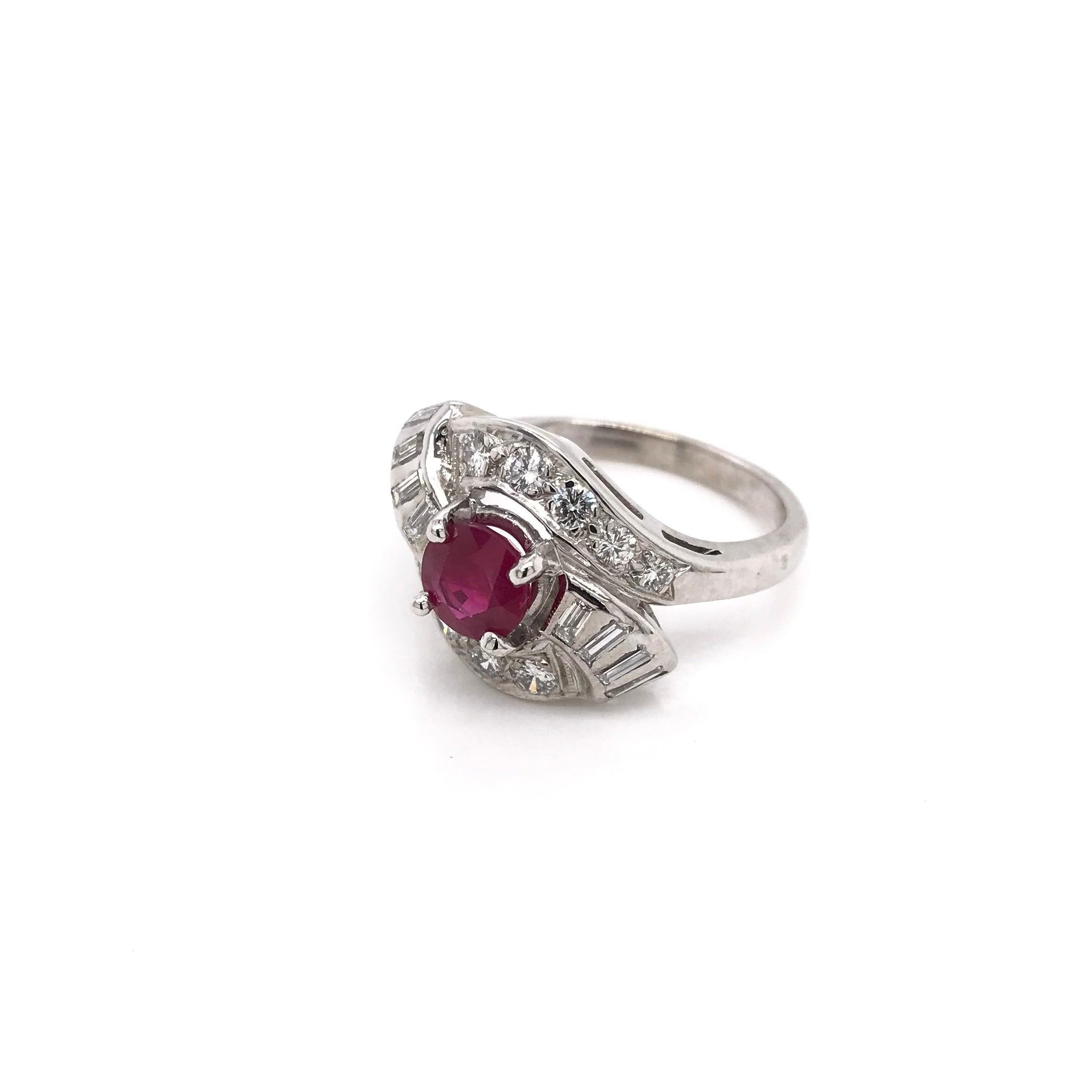 This piece was crafted sometime during the Retro design era ( 1940-1960 ). The setting is 14k white gold and features a beautiful center ruby. The ruby is richly hued and measures approximately 1.01 carats. The 14k white gold setting features 10