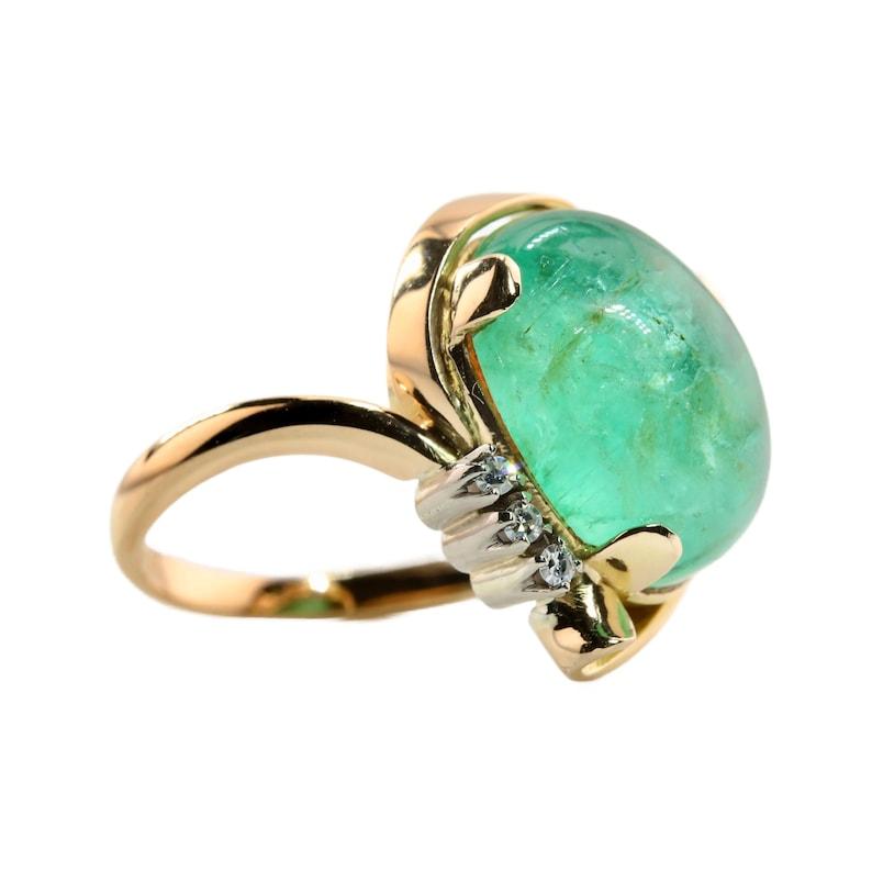 Aston Estate Jewelry Presents:

A mid century cabochon cut Emerald abstract motif ring in 18 karat gold, and platinum. Centered by a 10.50 carat cabochon cut emerald of very vivid and lively minty green color. Accented by four brilliant cut diamonds
