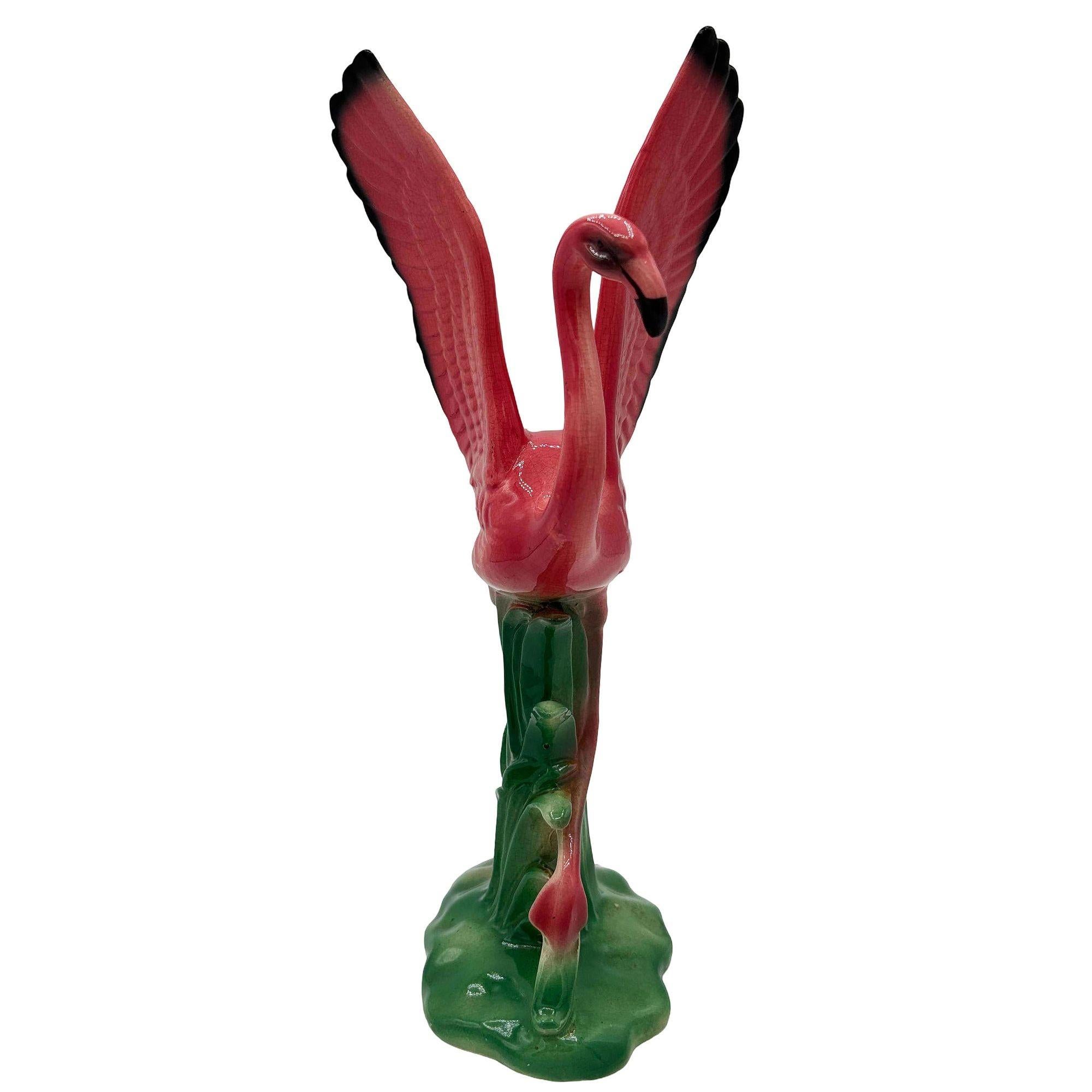 Mid-century pink and green ceramic open-wing flamingo tabletop pottery statue by Leftons. The statue features a beautifully detailed pink flamingo flying over a grassy field. It comes in a gloss finish that highlights the rich pinks, greens, and