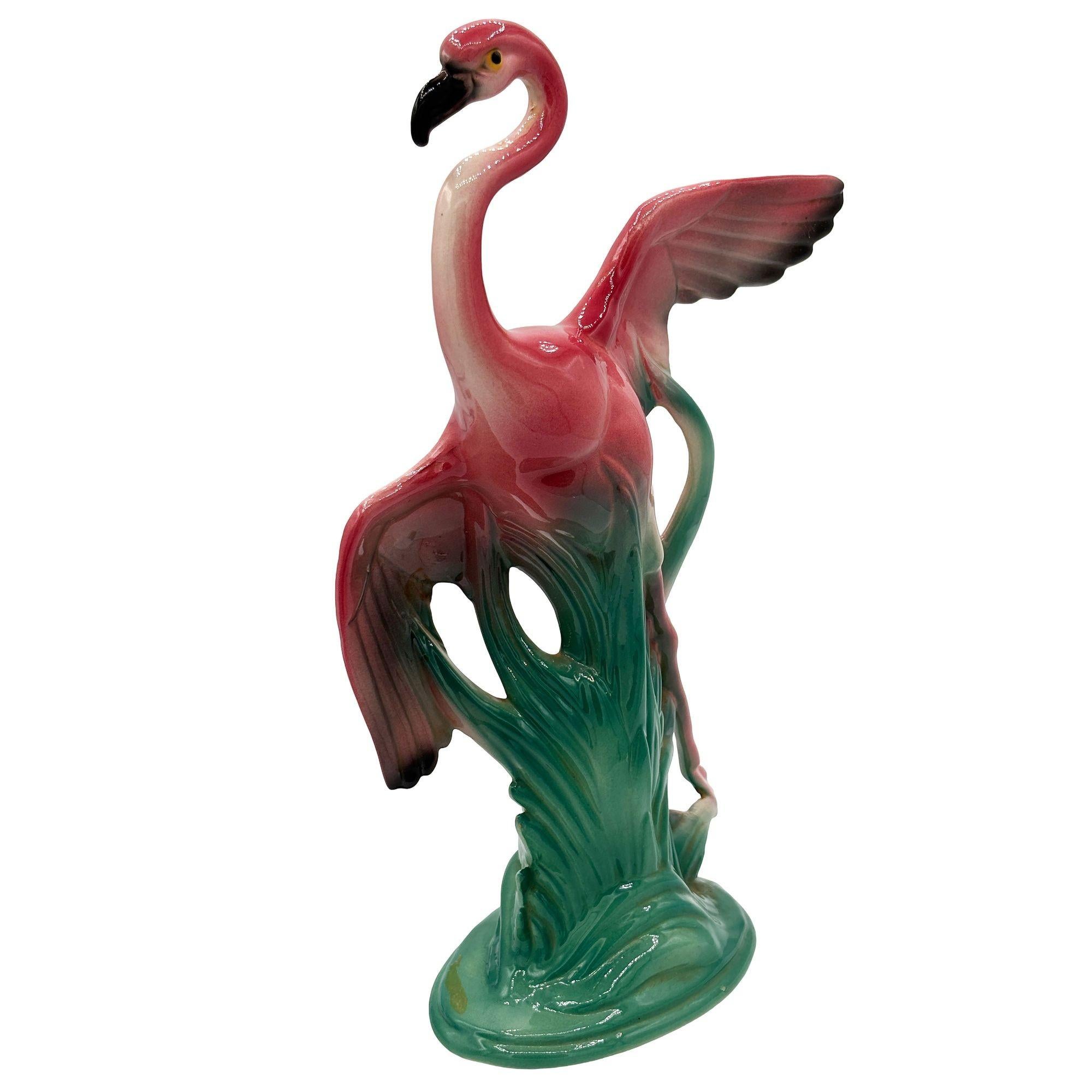 Set of two Mid-century pink and green ceramic open-wing flamingo tabletop pottery statues. Each statue features a beautifully detailed pink flamingo flying over a grassy field. The Large statue features a flamingo in mid-flight with its matching