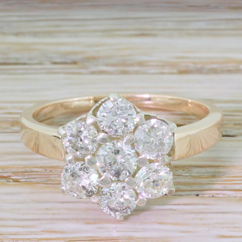 A dazzling Mid Century diamond cluster ring. The seven round brilliant cut stones – all high white and bursting with life and sparkle – are claw-set within a finely pierced white gold gallery which sit on a slim and flat rose gold
