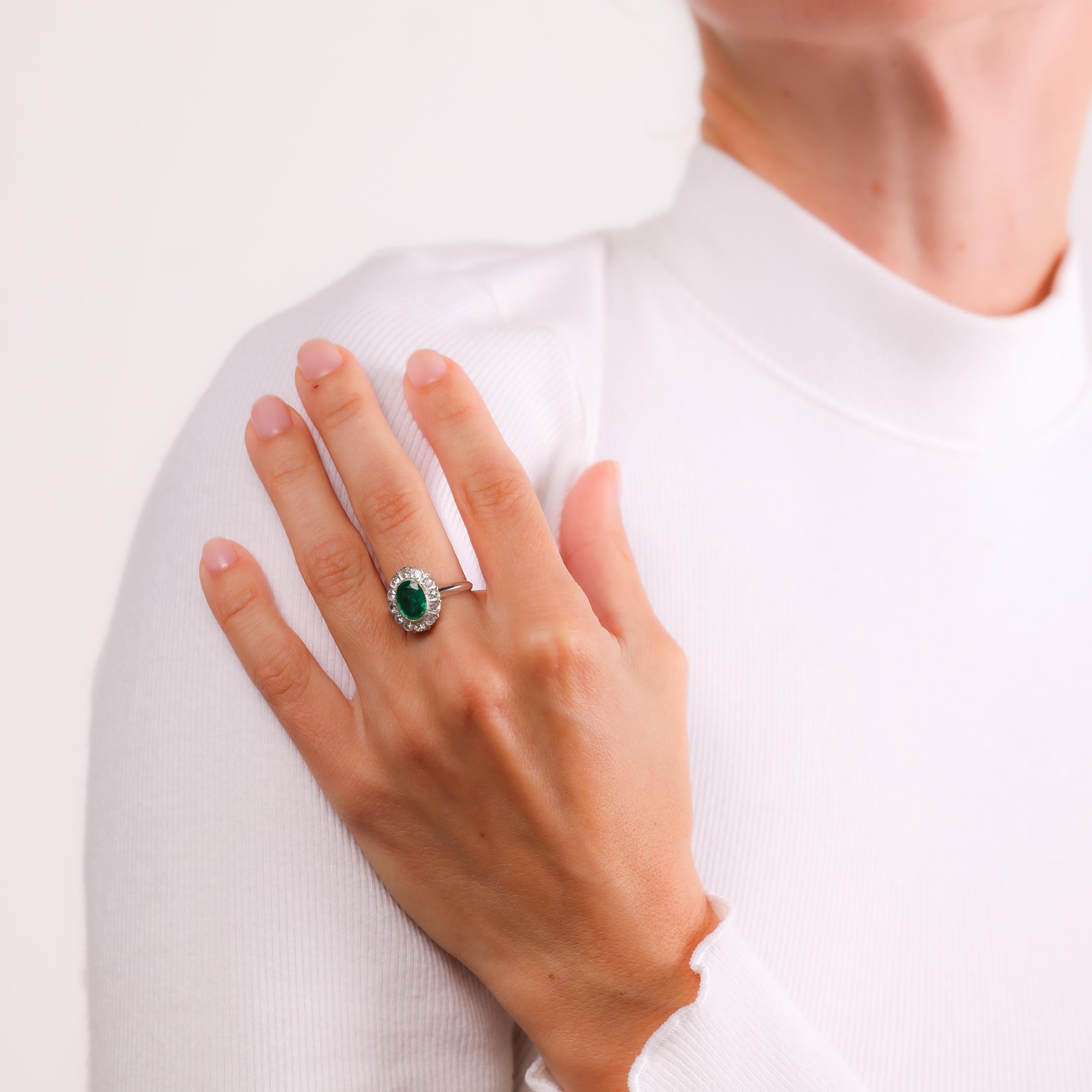 This Mid Century cluster ring in 10k white gold highlights a vivid Zambian emerald surrounded by sparkling diamonds. A timeless and elegant design from the 1960s.

Certificate: GL #533-218
Center stone: Oval cut emerald 
Weight: Approximately 1.25