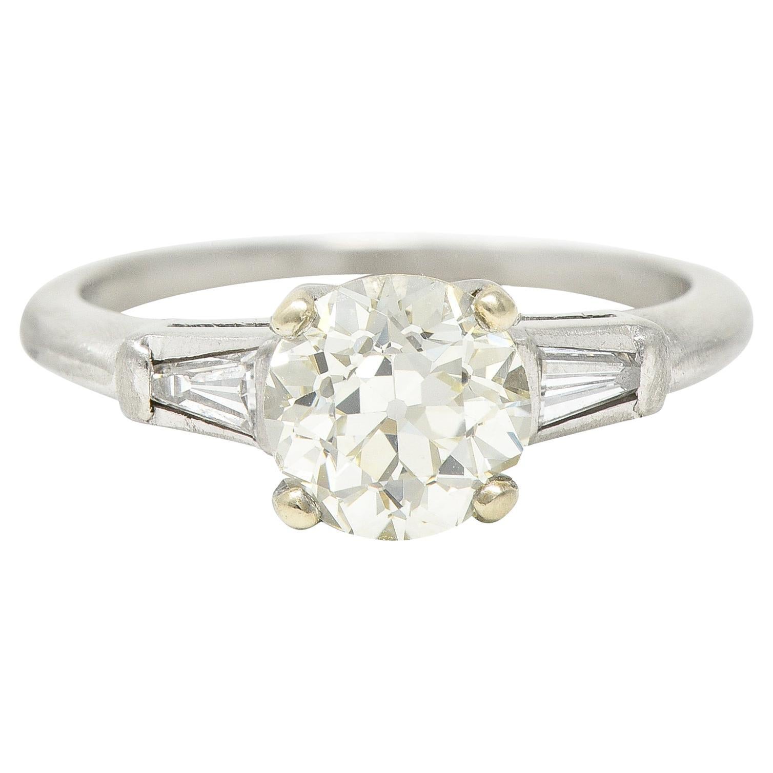 Featuring an old European cut diamond weighing 1.19 carats - M/N color with VS1 clarity. Prong set and flanked by cathedral shoulders bar set with tapered baguette diamonds. Weighing collectively approximately 0.15 carat - H/I color with VS clarity.
