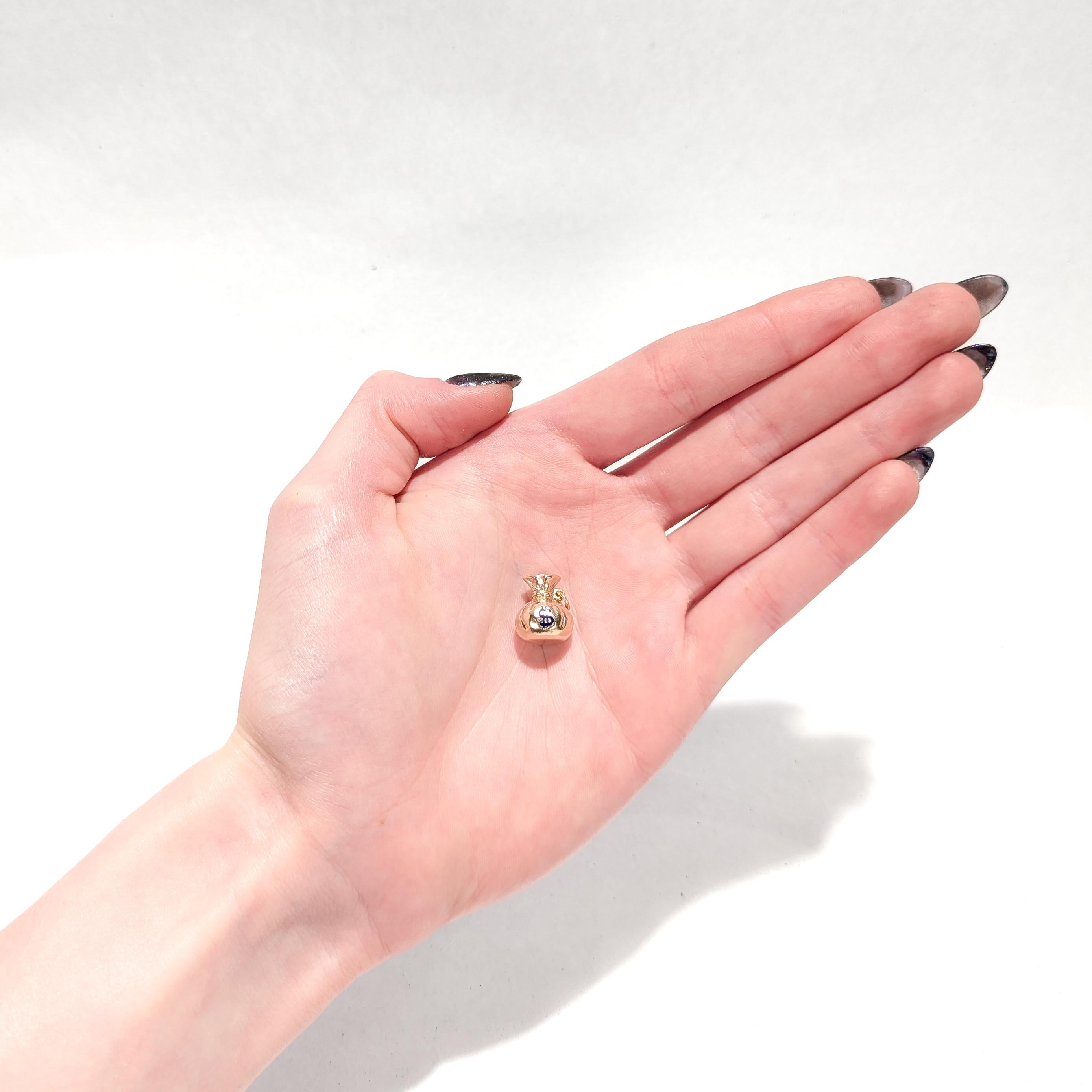 A fine Mid-Century charm for a bracelet.

In 14 karat yellow gold.

In the form of a figural, three-dimensional money bag or sack with a blue enamel dollar sign to the front.

Fixed with an integral bail and a jump ring.

Marked 14k to the jump