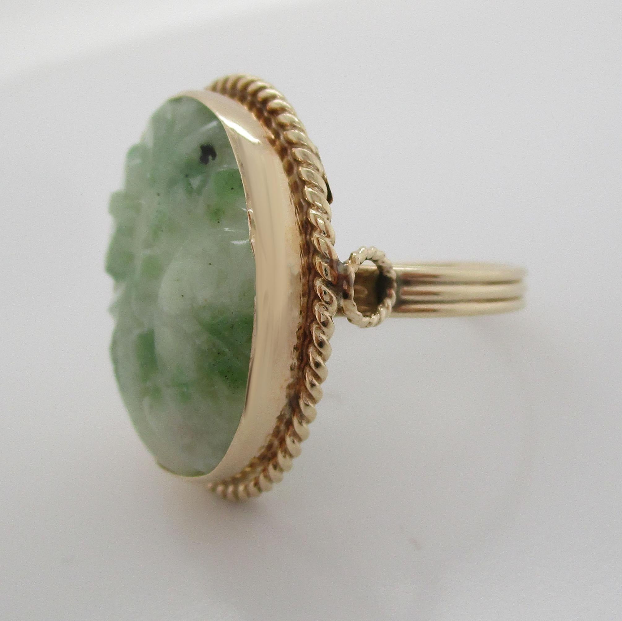 This remarkable mid-century statement ring brings together bright 14k yellow gold and soft green jade carved with an elegant pattern. The ring is the picture of elegance, from the complementary contrast of bright yellow gold and mottled green to the
