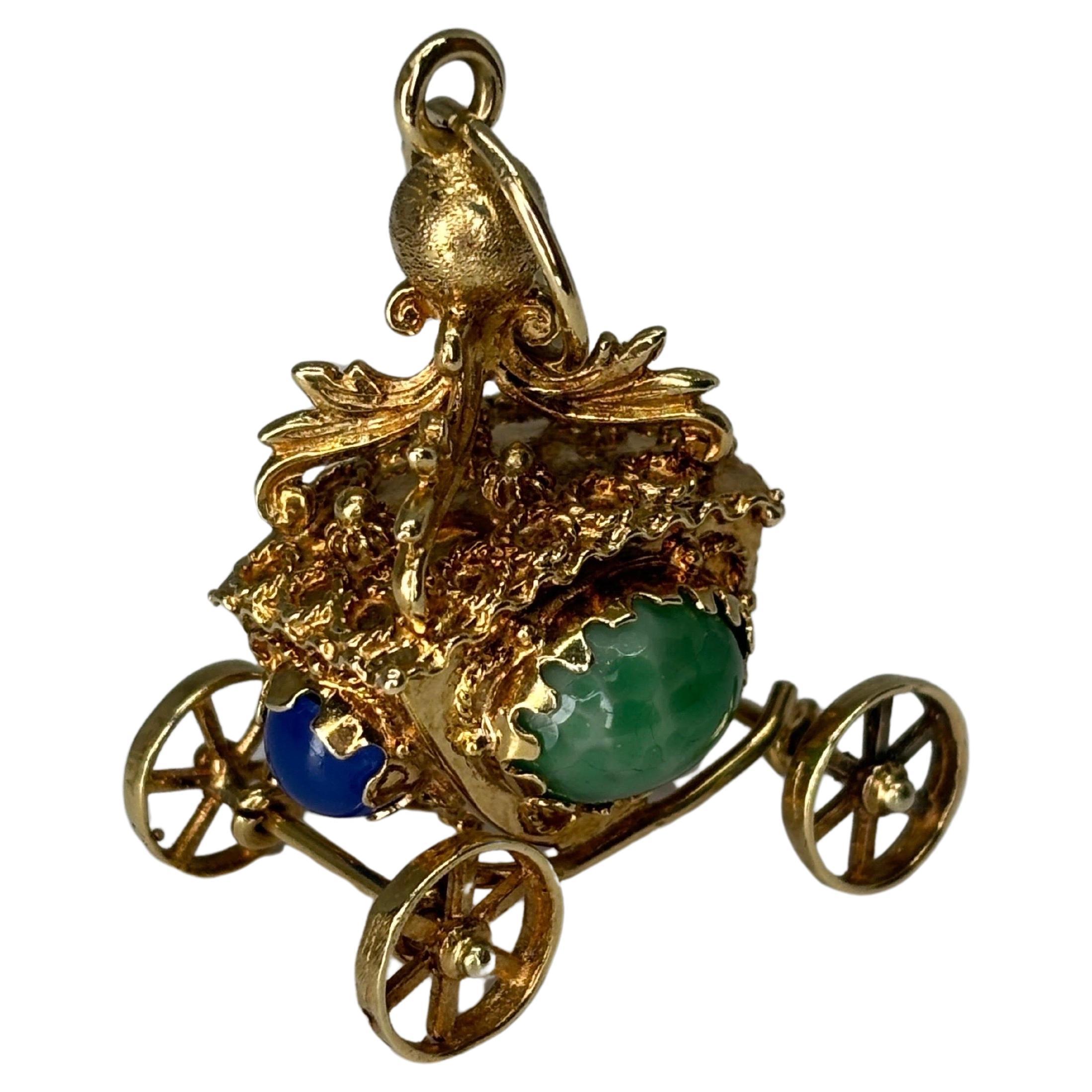 Enchanting 14k yellow gold Etruscan Revival royal carriage coach carriage with movable wheels and accented with blue and green chalcedony cabochon gems.  

This charm embodies the intricate gold work and elaborate designs characteristic of Etruscan