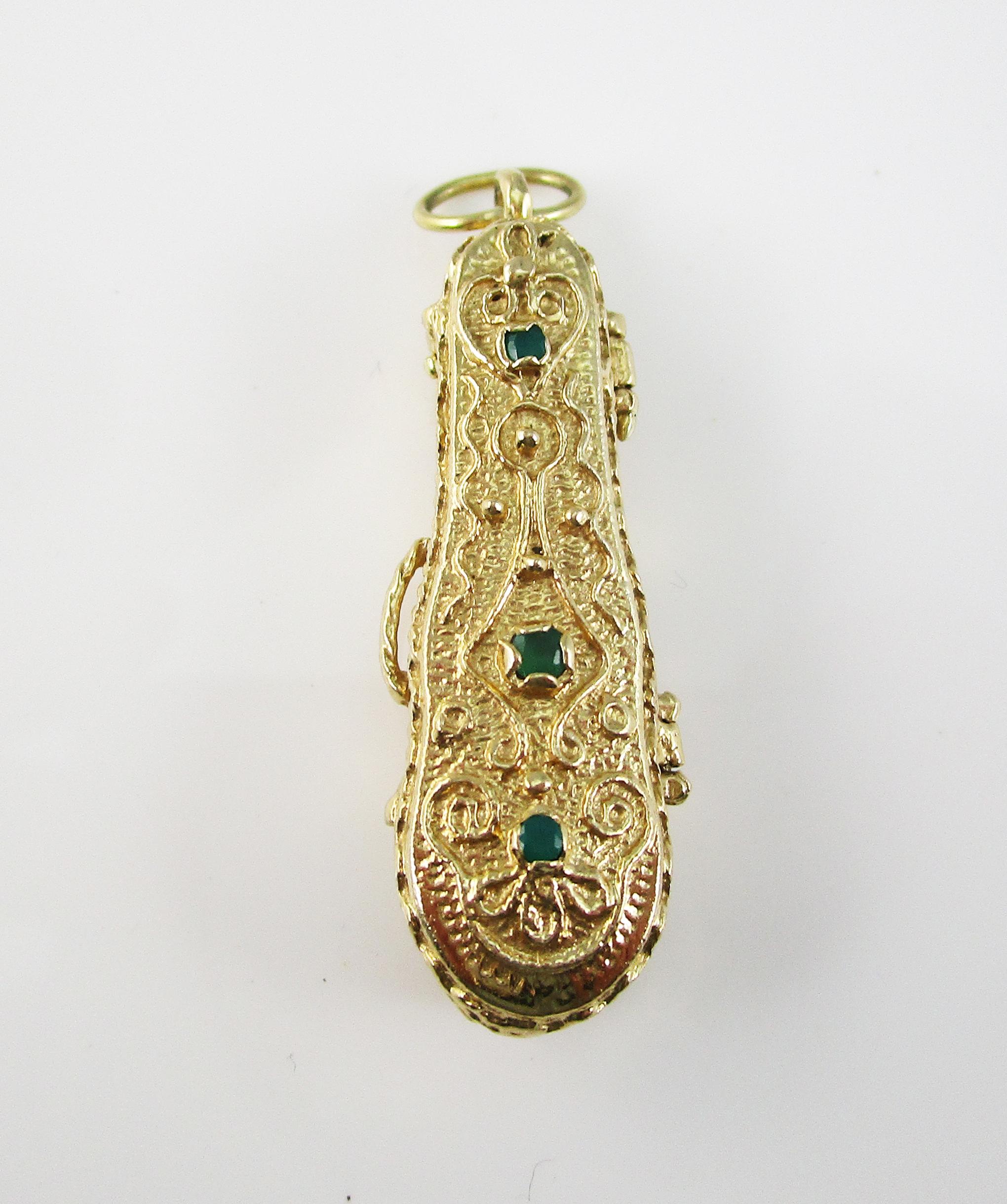 This crescendo of a mid-century charm is in 14k yellow gold and features stunning engraved and layered details and delicate green emerald accents. The pendant is in the shape of a violin case and opens to reveal a 14k yellow gold violin within!! The