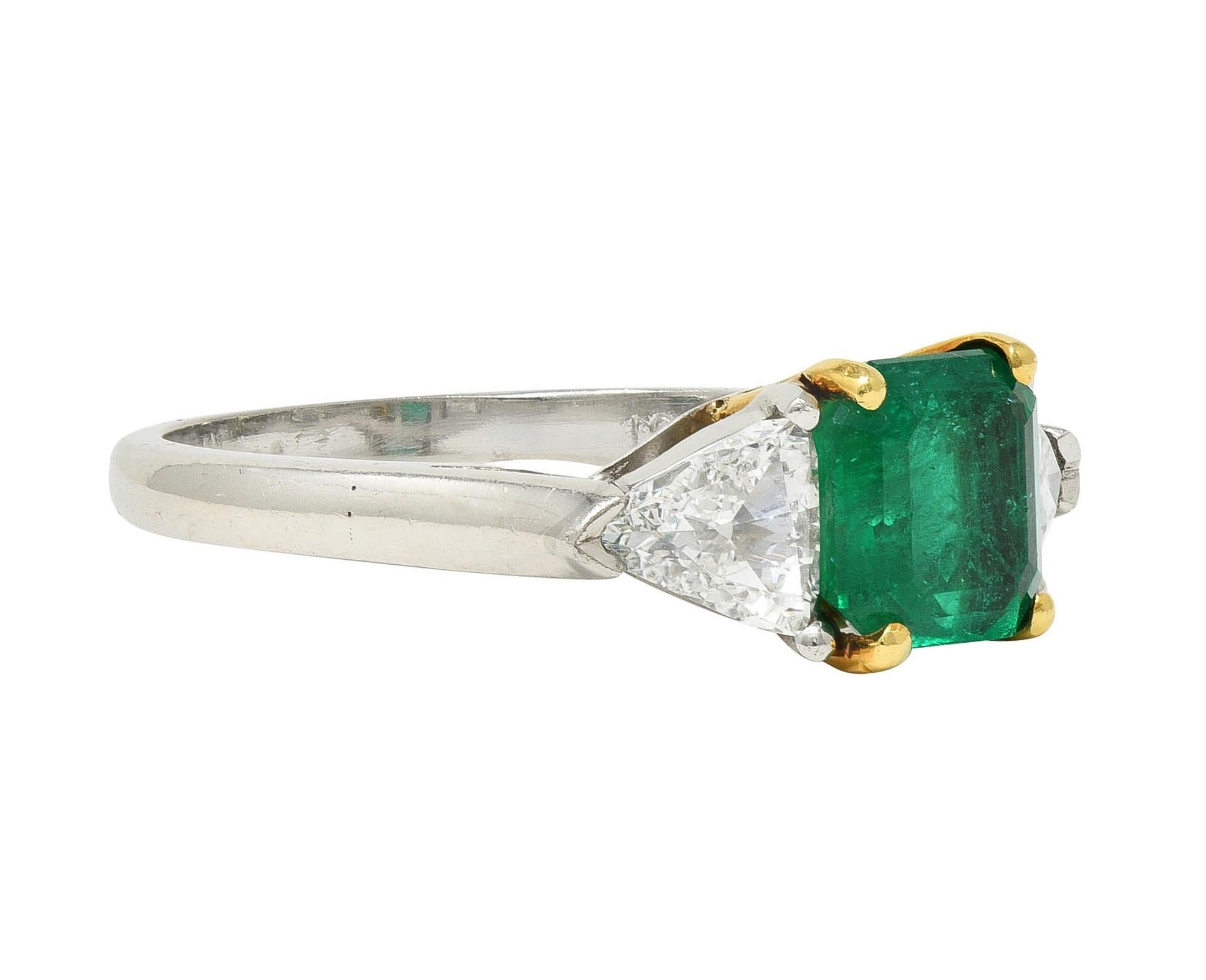 Centering an emerald cut emerald weighing 1.20 carats total - transparent medium green
Natural Colombian in origin with minor traditional (F2) clarity enhancement
Set with yellow gold split talon prongs in gold and platinum basket
Flanked by old