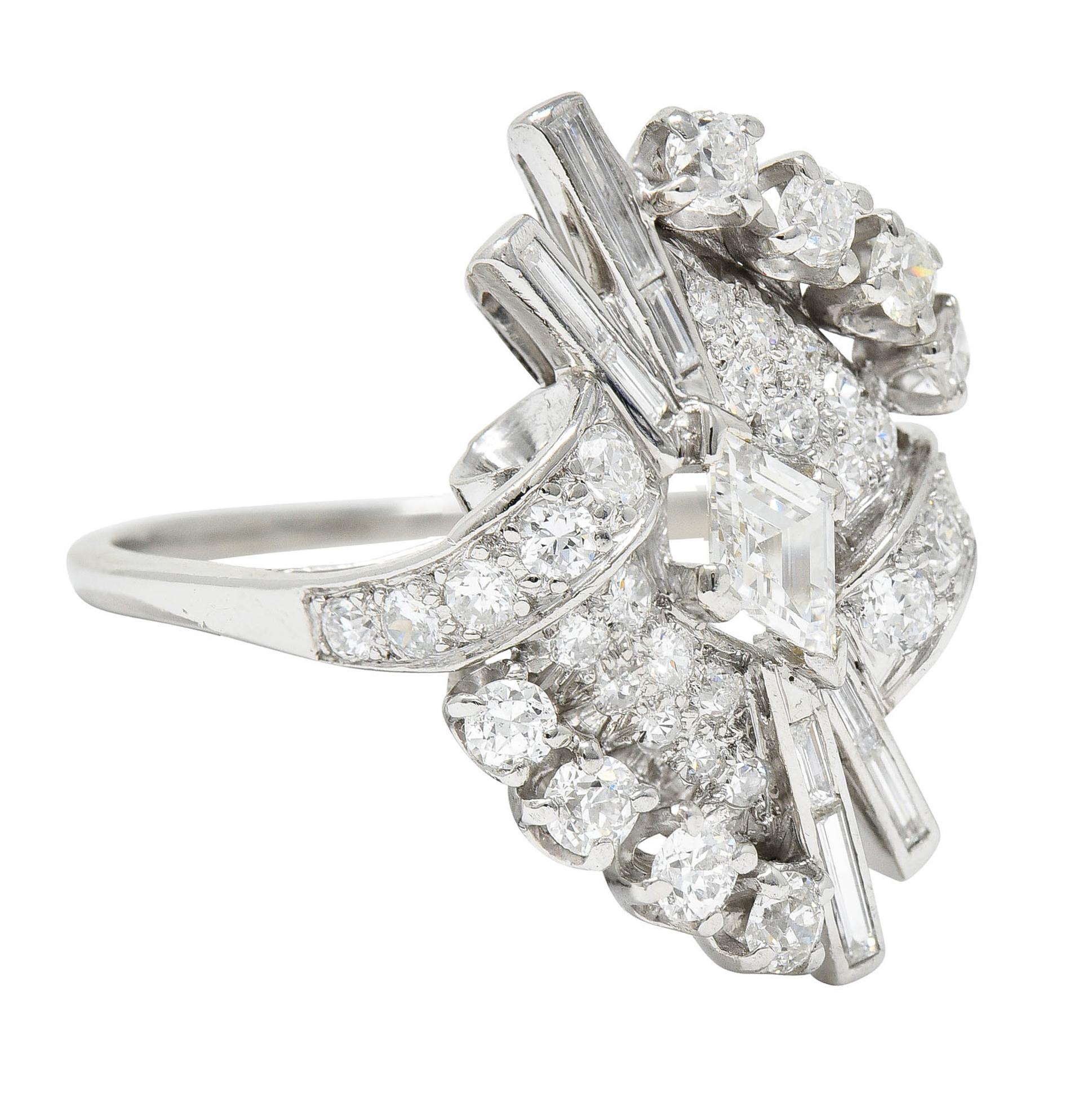 Stylized bypass ring features a starburst motif with ribboned scrolled shoulders

Centering a navette stepped cut diamond weighing approximately 0.35 carat - G/H color with VS clarity

Linear extensions are channel set with baguette cut diamonds