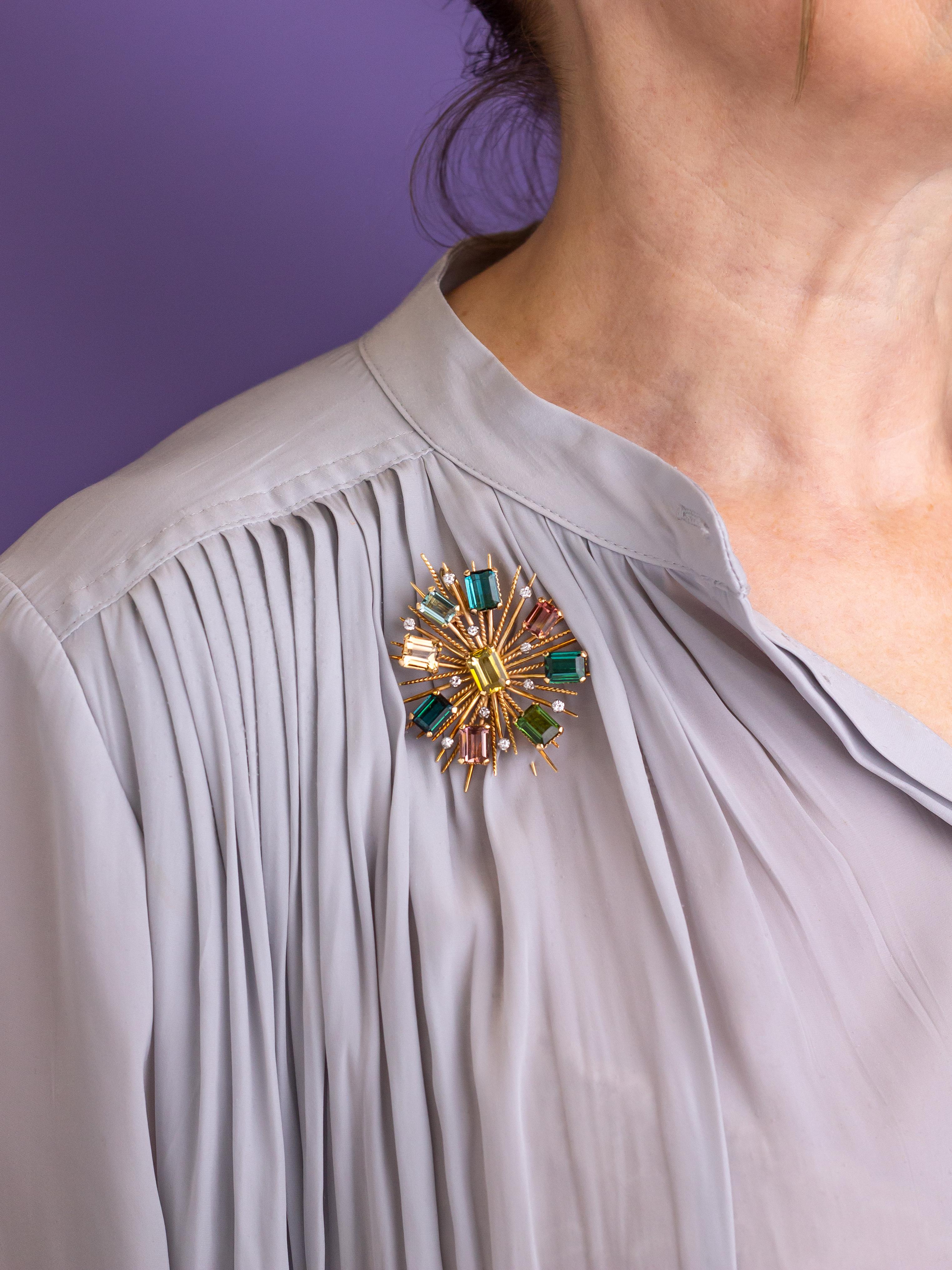 This exceptional mid century brooch pendant has been crafted from 18 karat rose and white gold and set with tourmalines and diamonds. The piece features nine emerald cut tourmalines that are classed as, bright mid yellow, bright dark greenish blue,
