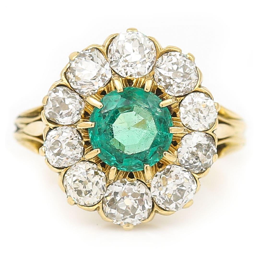 A magnificent mid century 18ct gold round emerald and old cut diamond cluster ring dating from the middle of the 20th century, circa 1940. This special ring boasts a central round cut emerald of approx 2.7ct around which 10 old cut diamonds sit
