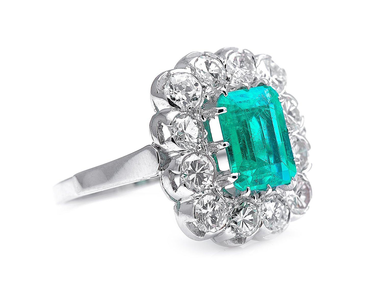Emerald and diamond ring, mid 20th century. This mid-century cluster ring is set with a step-cut Colombian emerald weighing approximately 1.6 carats, in an attractive, slightly bluish green shade with excellent transparency. Colombia has