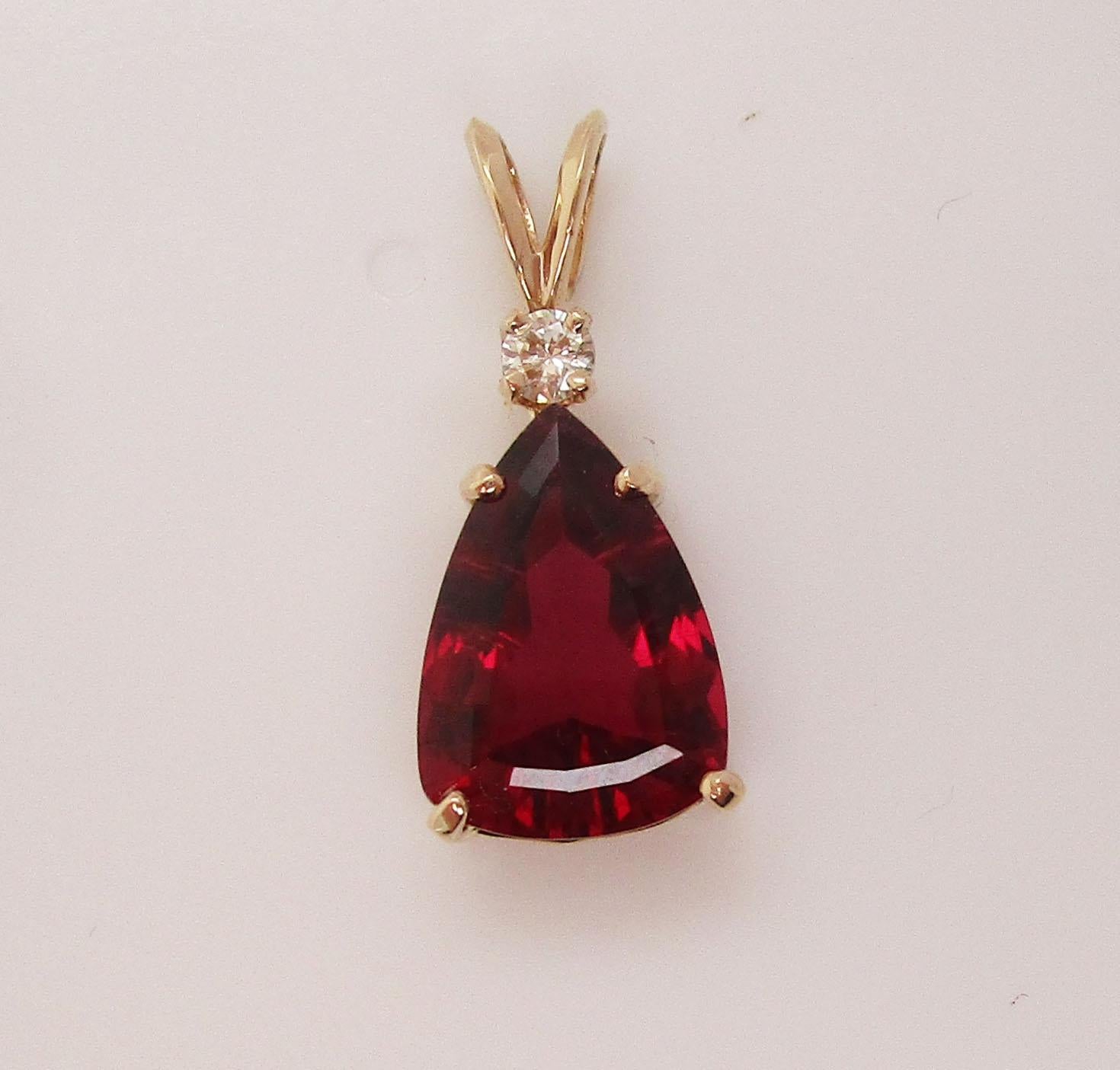This is an absolutely gorgeous mid-century 18k yellow gold pendant with a stunning, deep red rubellite center and bright white diamond accent! The pendant has a beautiful tear drop shape that is unique and serves as the perfect frame for the