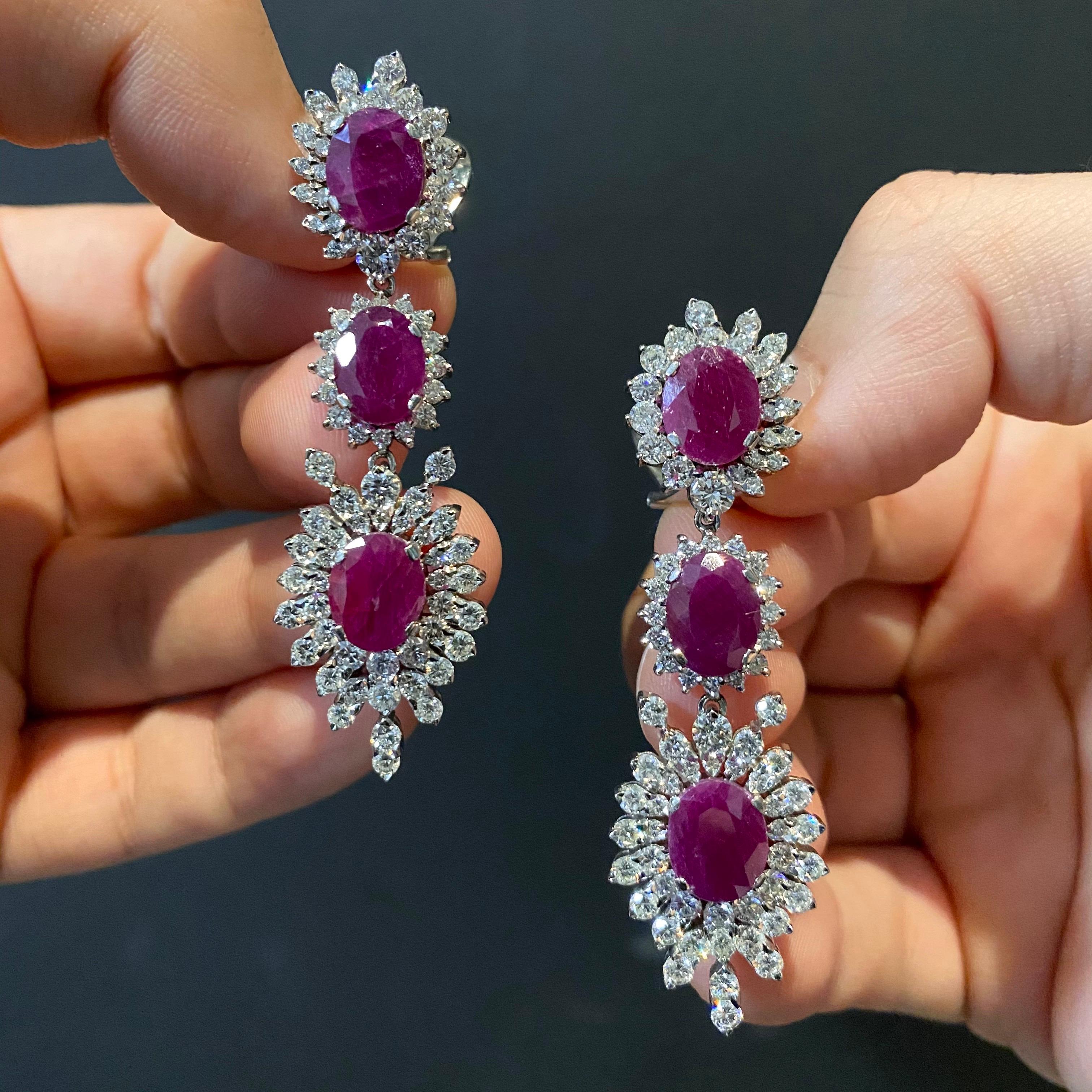 A Pair of Mid-Century 15.23ct Ruby and 8.10ct Diamond Cluster Drop Earrings in Platinum and 19.2 Karat White Gold, circa 1950s/1960s. Each earring is composed of three vertically articulated oval-shape ruby and round brilliant-cut diamond clusters