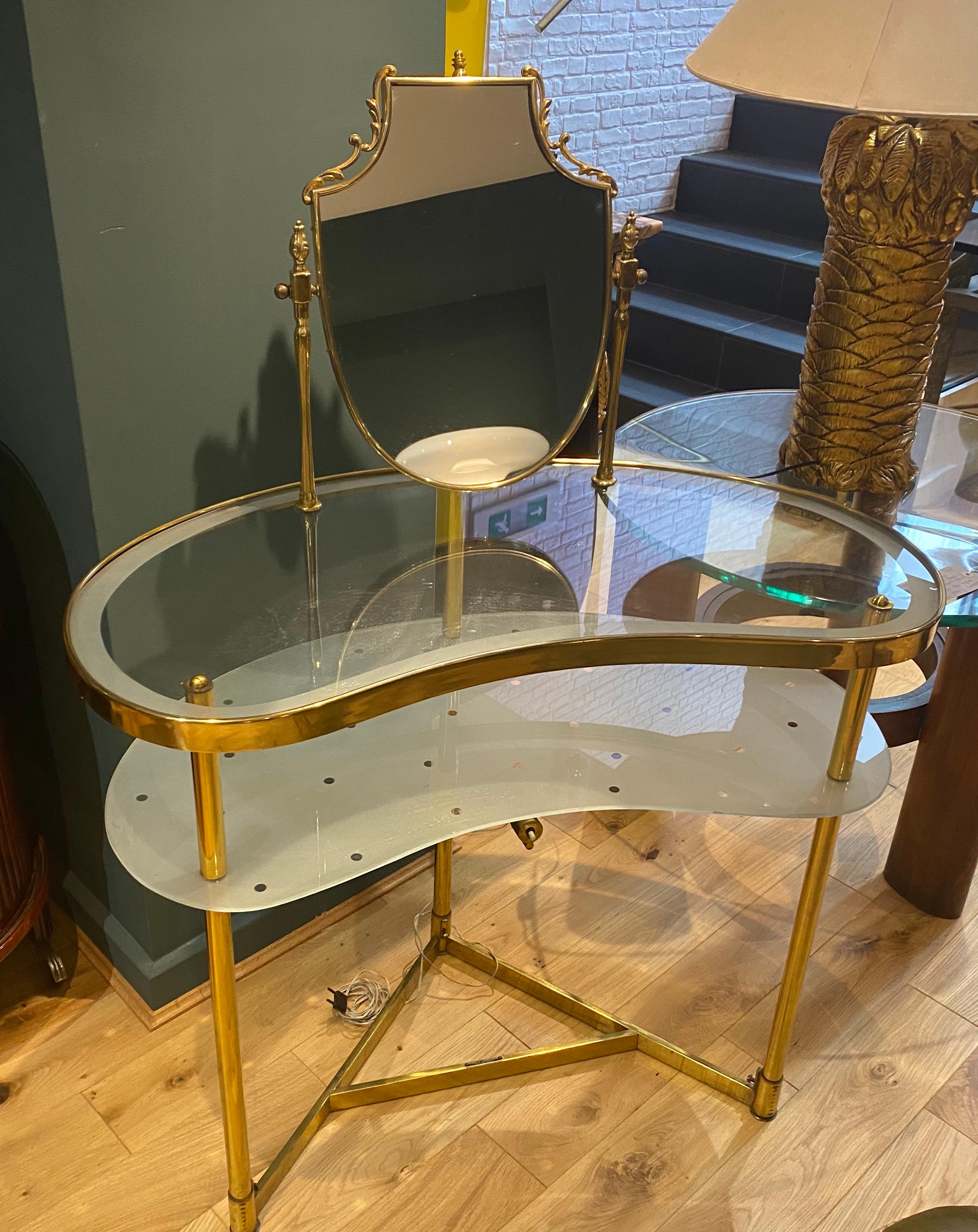 A fabulous 2 tiered 1950s glass and brass vanity table with adjustable mirror in a decorative frame. The lower shelf is etched with polka dots and illuminated by a light underneath.
Stamped MODELLO LAMPADARTE - DEPOSITATO -