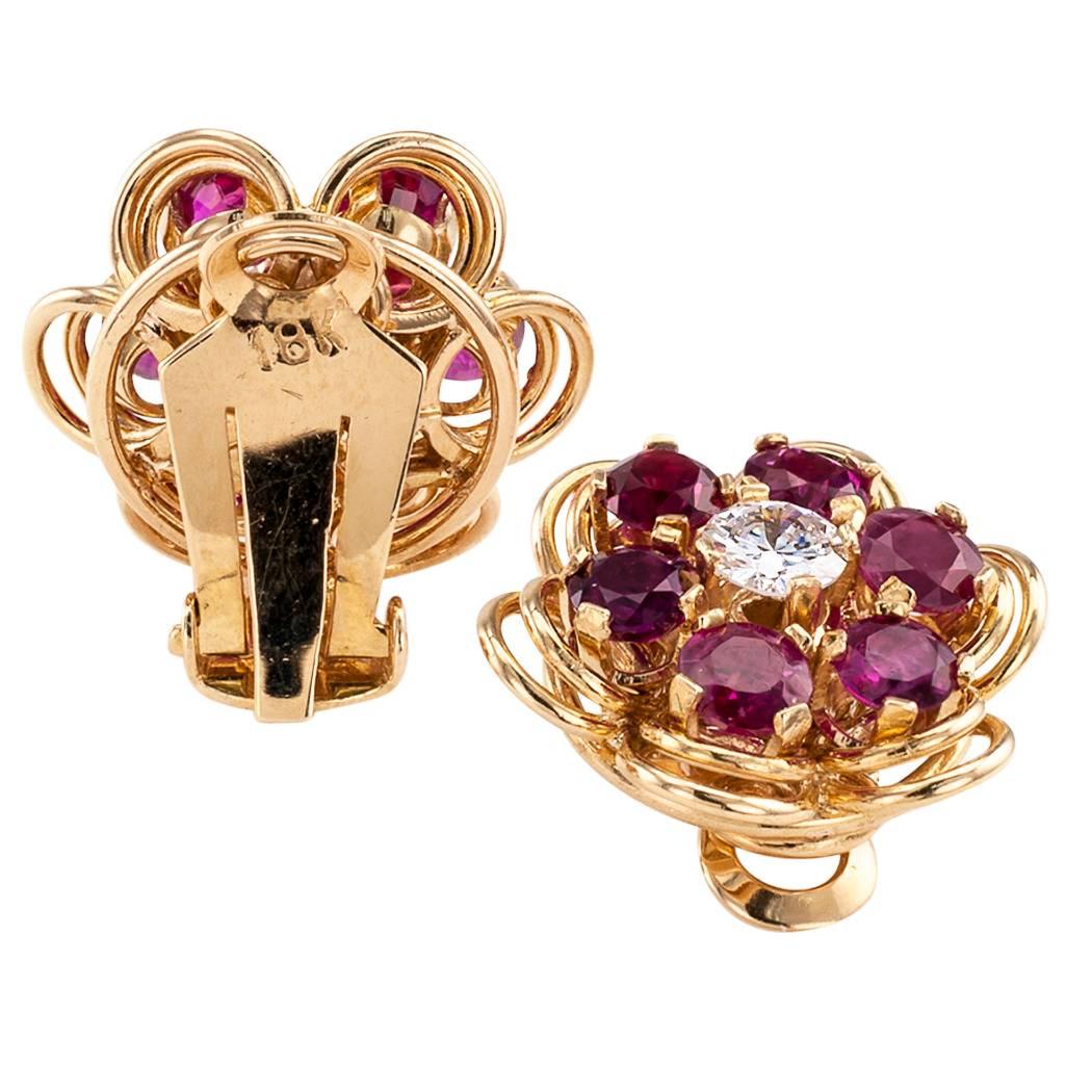Mid century ruby and diamond gold ear clips circa 1950. The hand fabricated rosette designs centering a pair of round diamonds together weighing approximately 0.70 carat, approximately H - I color and VS - SI clarity, encircled by round rubies