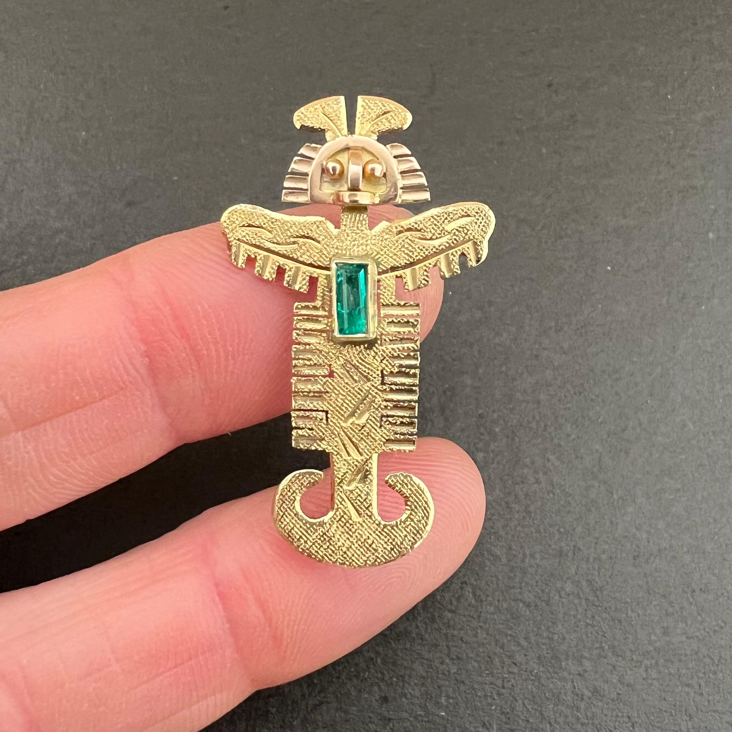 An 18 karat yellow gold mid-century 1960's pre-Columbian Tolima pendant set with an emerald. The symmetrical pendant has engraved details and a gold satin finish. The pendant can also be worn as a brooch. 

This pendant in the Tolima style, comes